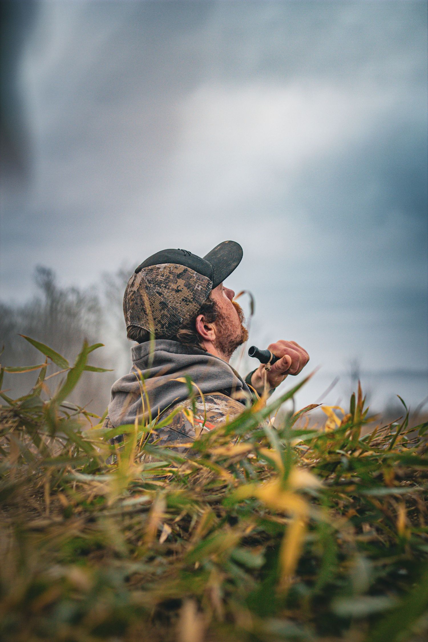 Low angle view of a hunter concealed in grass watching for waterfowl.