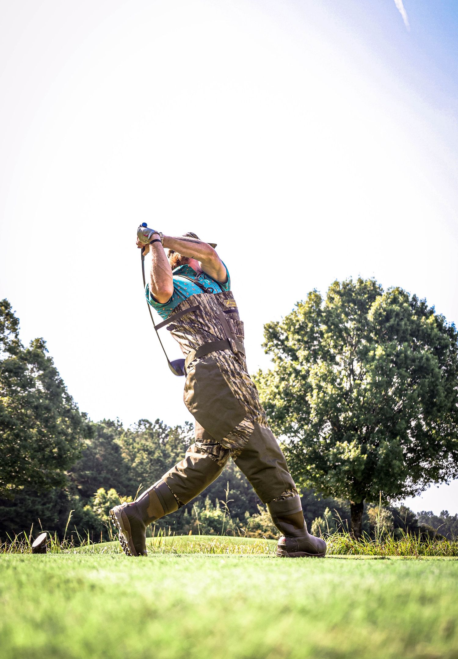 Low angle shot of hunters walking across a grassy field in camouflage gear.