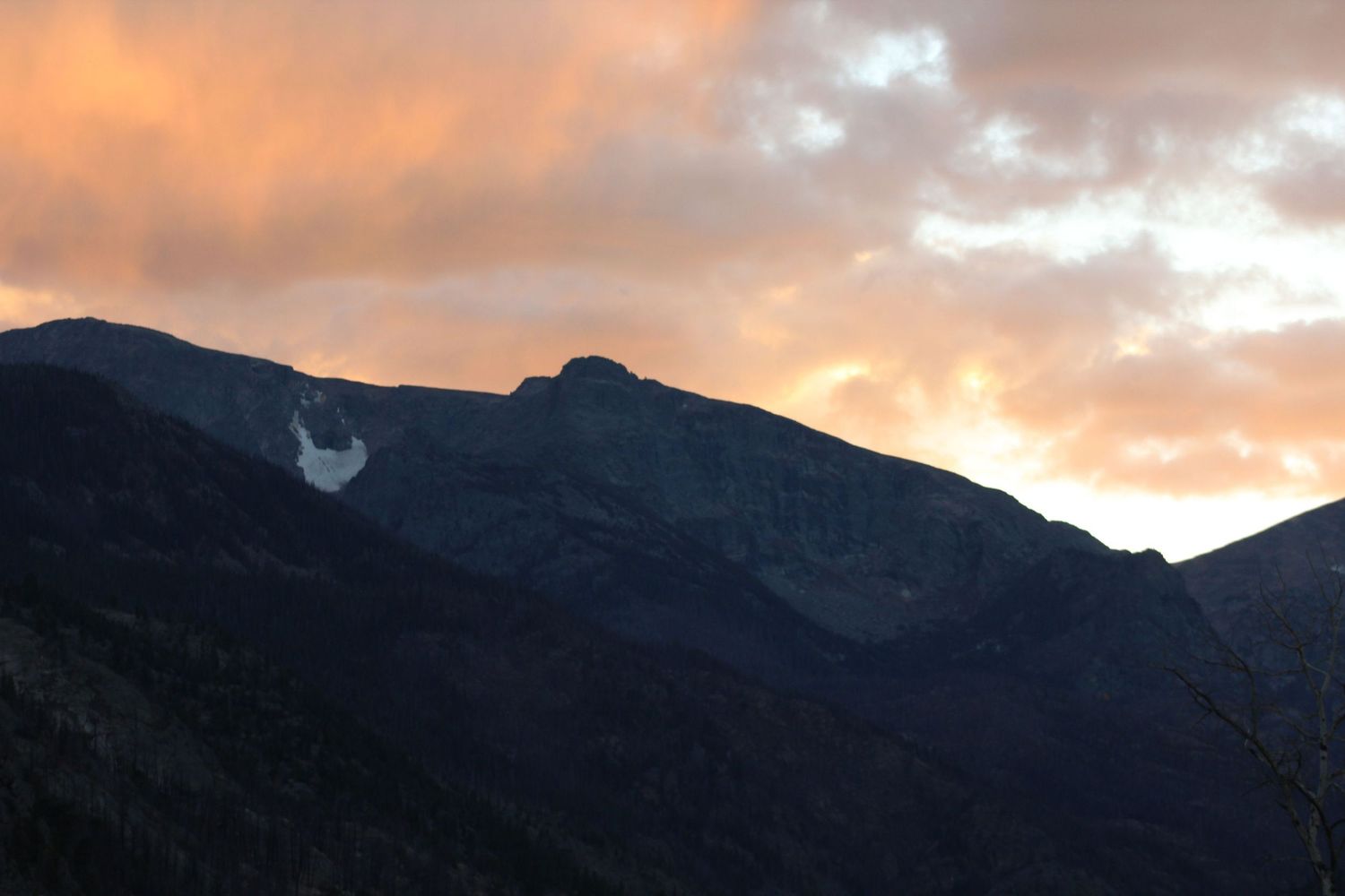 Dramatic mountain silhouettes against orange and purple sunset sky.