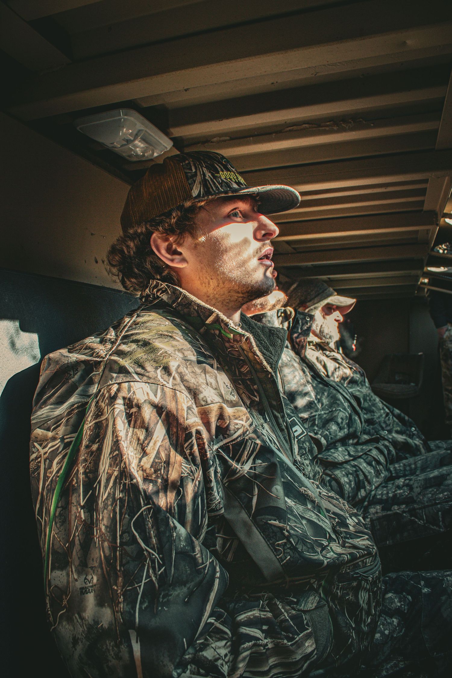 Hunter in camouflage gear positioned in a wooden duck blind.