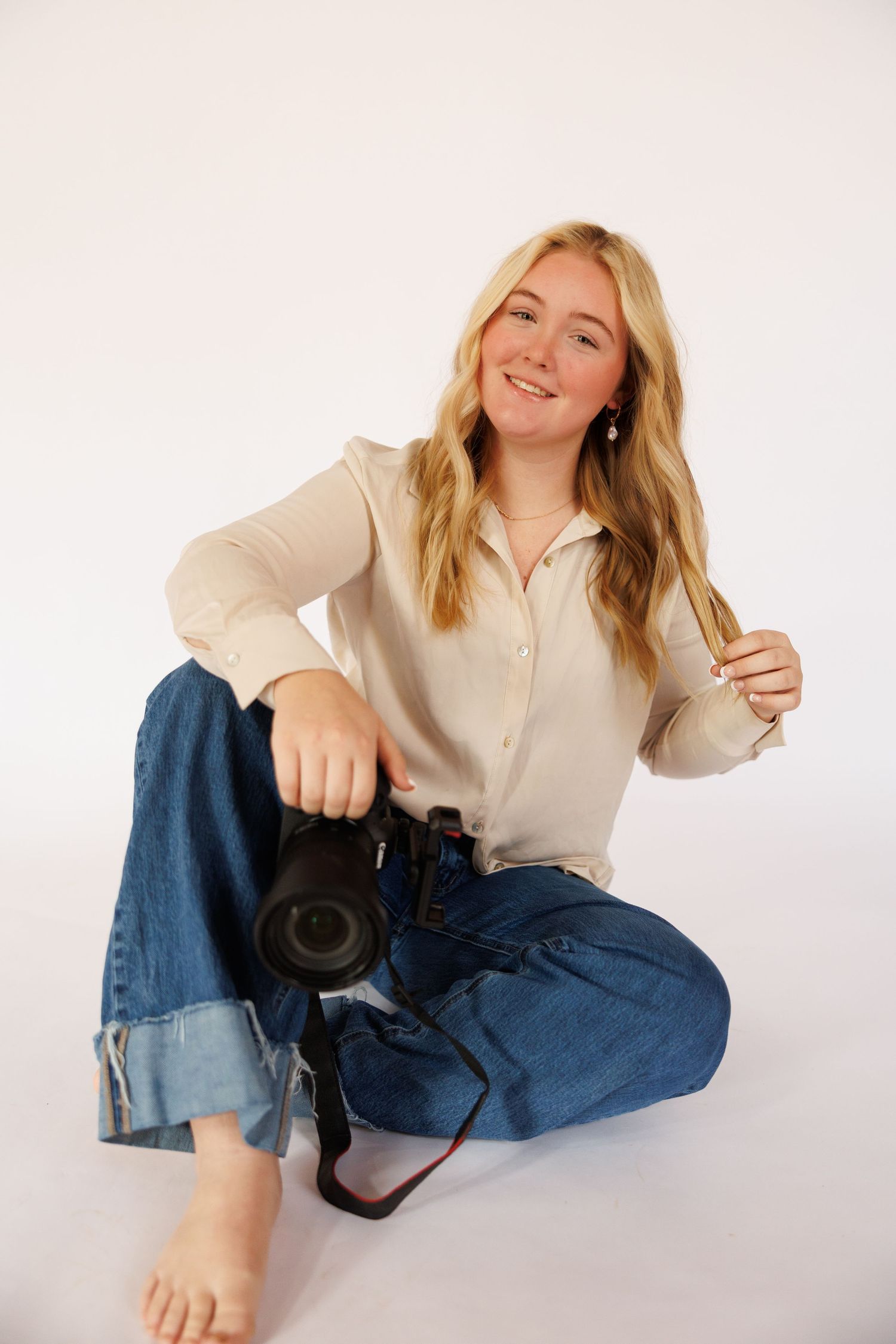 Blonde woman in white button-down shirt and jeans poses playfully against white background in photo series.