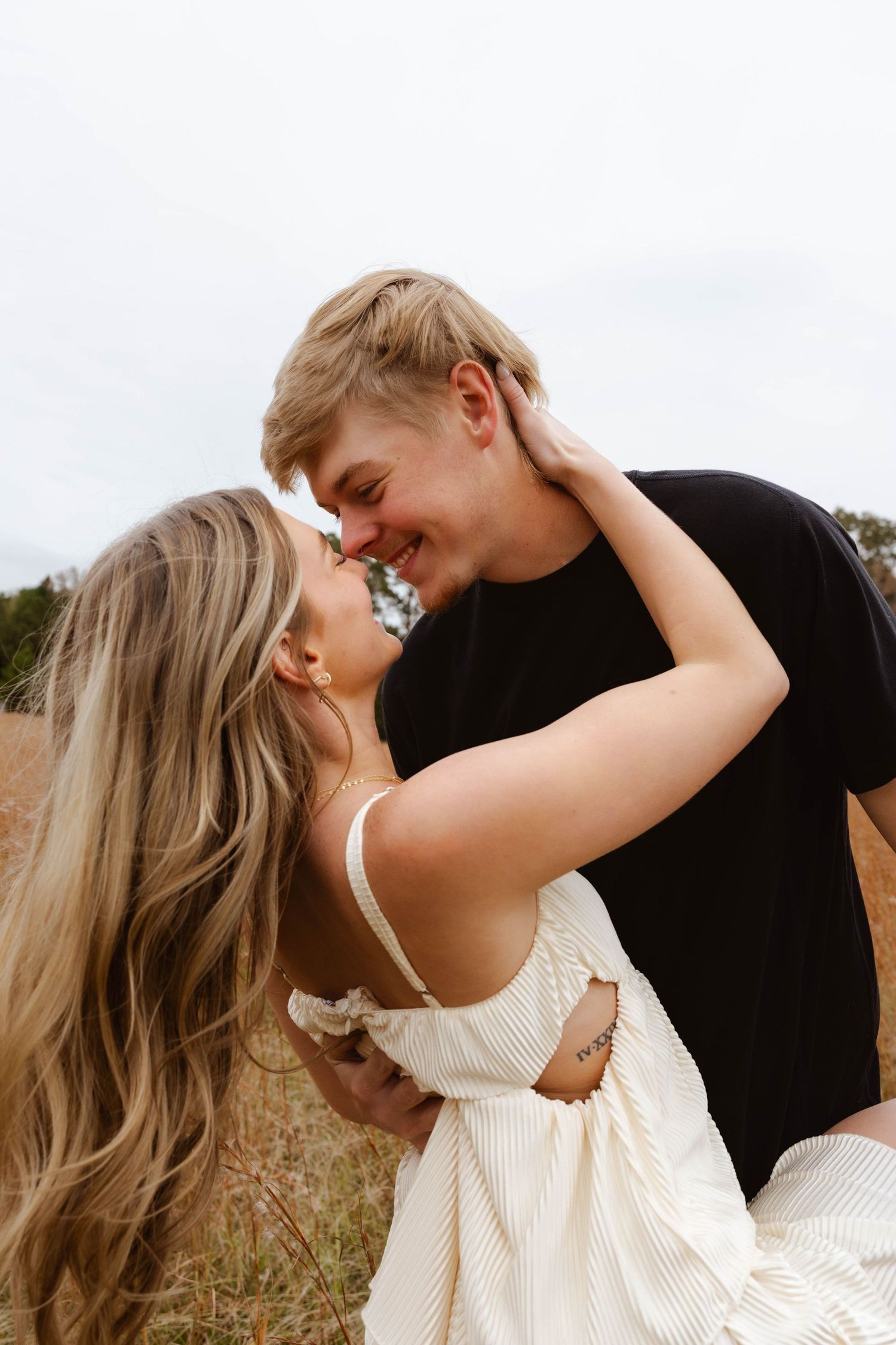 Intimate romantic moment between couple in field with dramatic lighting.