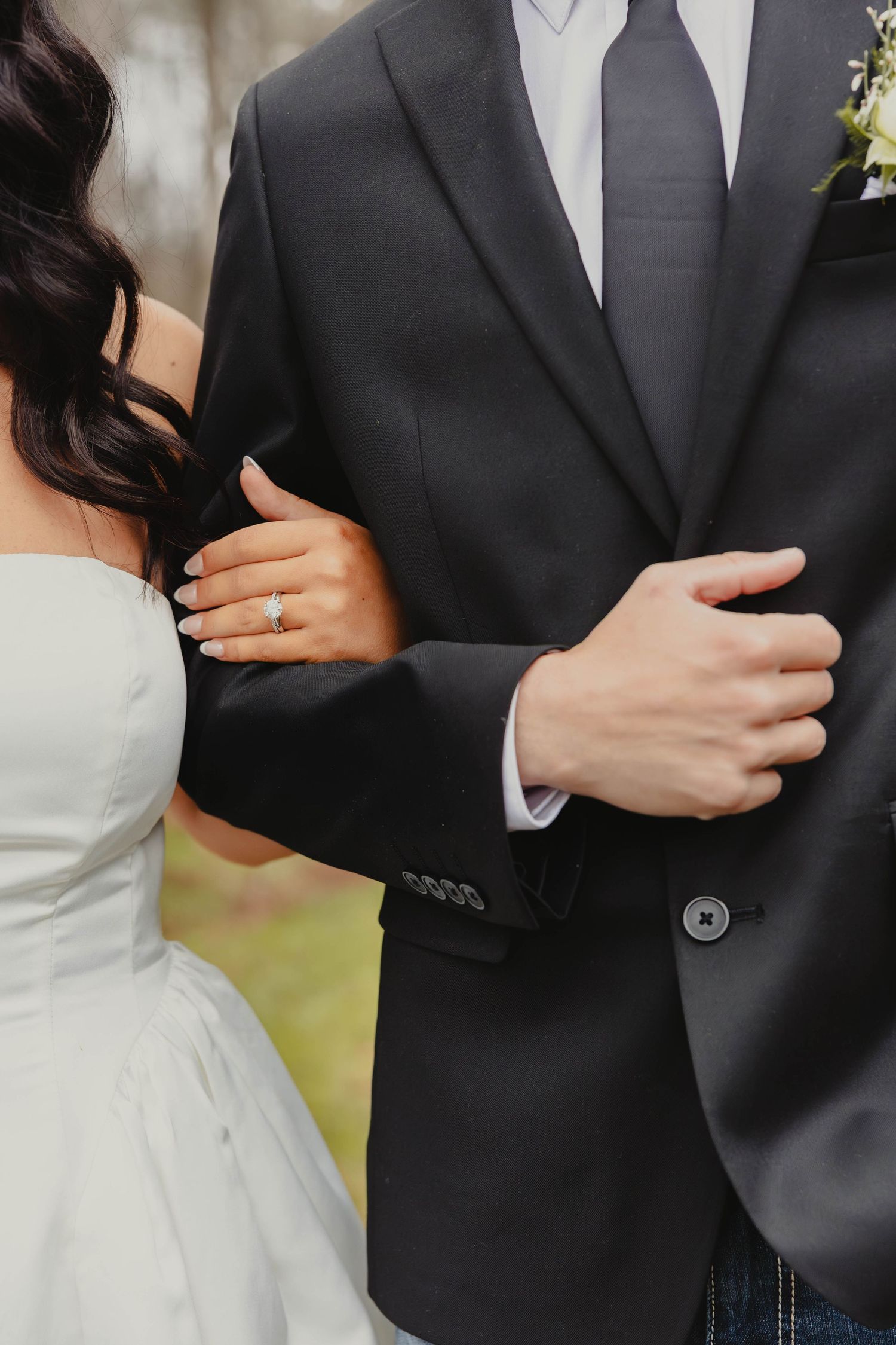 Close-up detail shots of a bride and groom embracing in formal wedding attire showing rings and formal wear details.