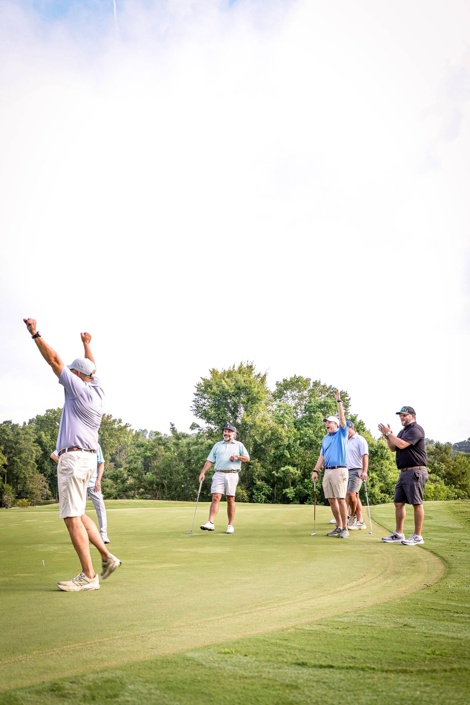 Golfers celebrating on a lush green course during a sunny day.
