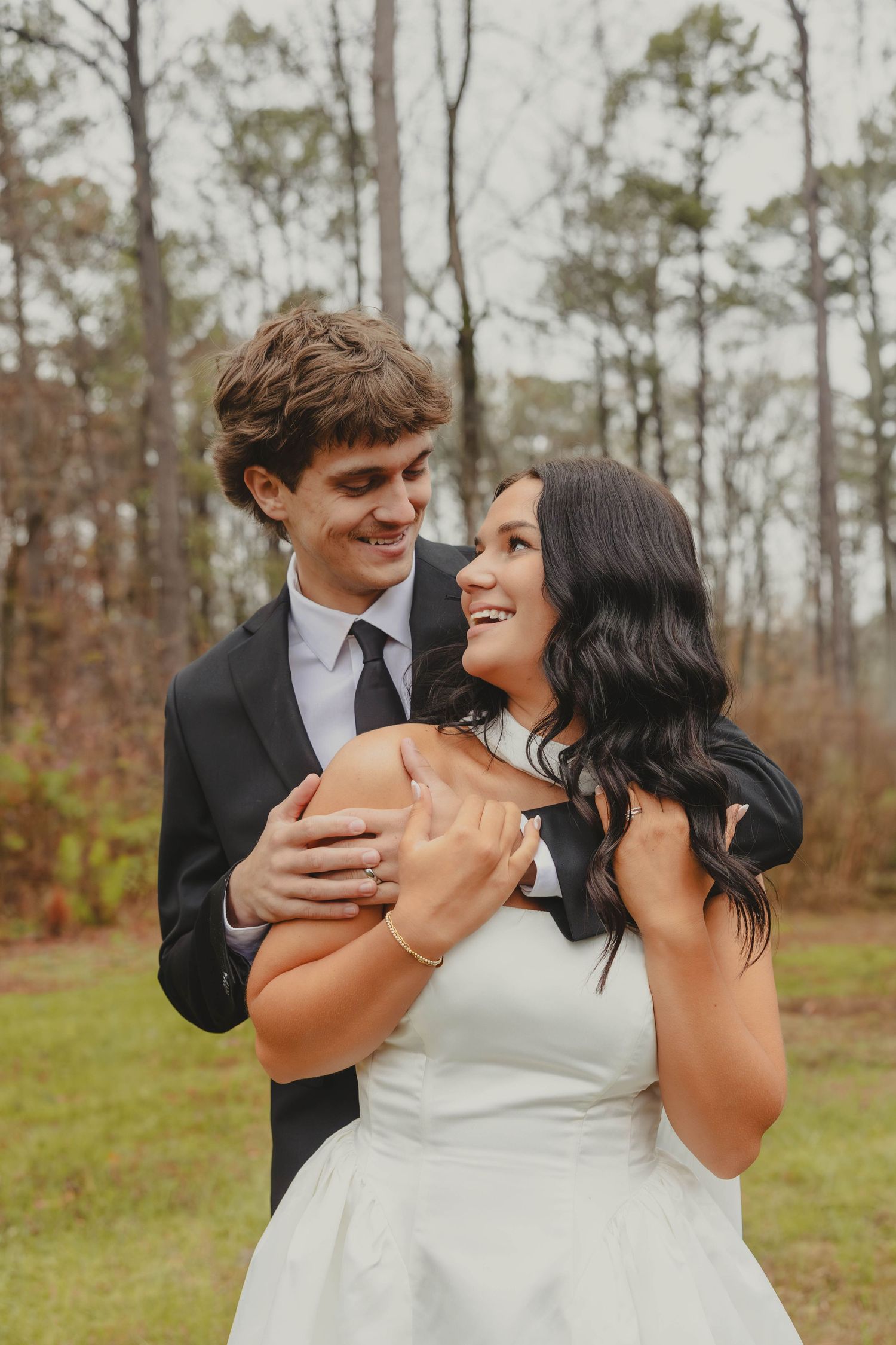 A joyful couple shares candid laughter and embraces during their outdoor autumn wedding photoshoot.
