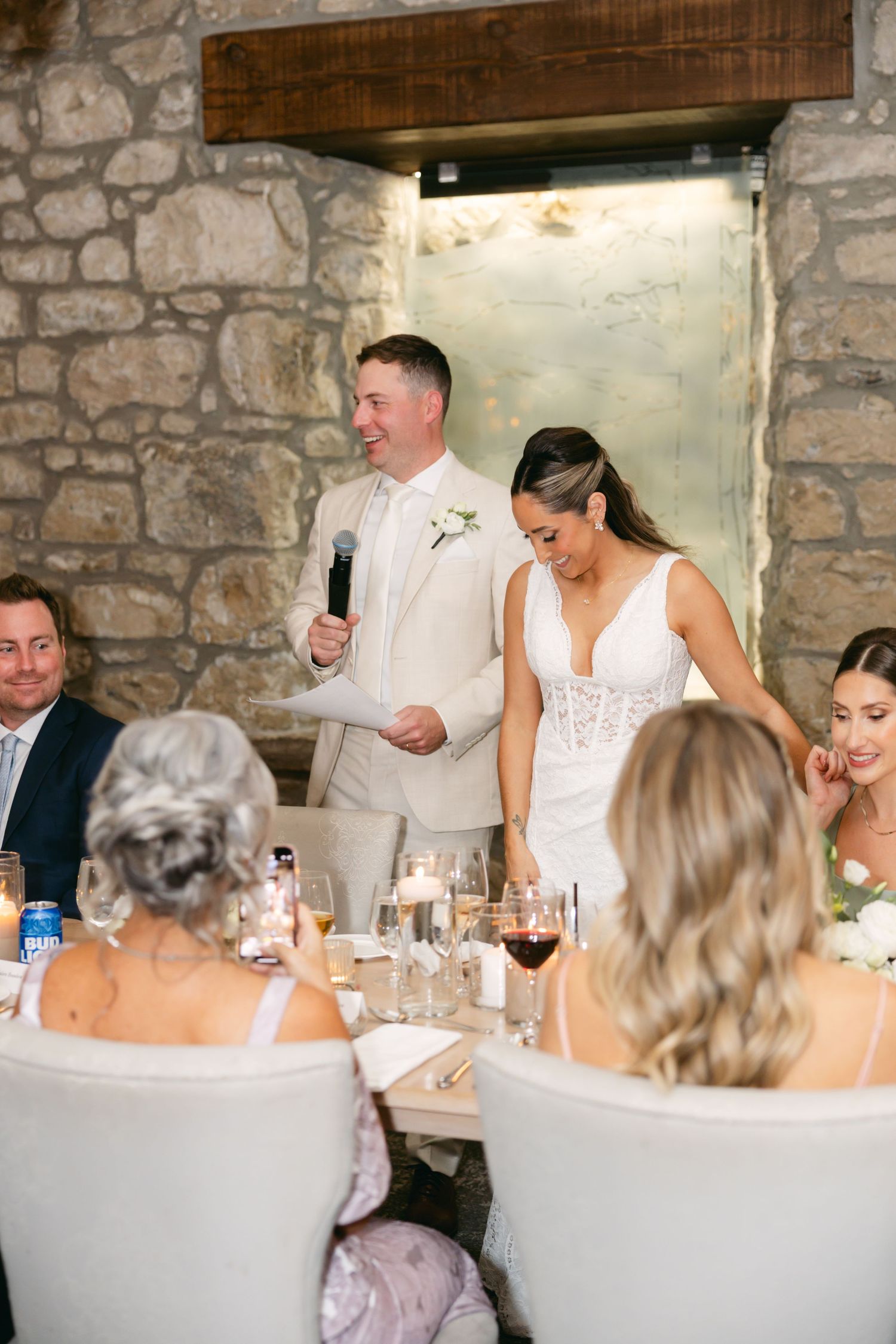 Wedding reception dinner in rustic stone venue with white decor.