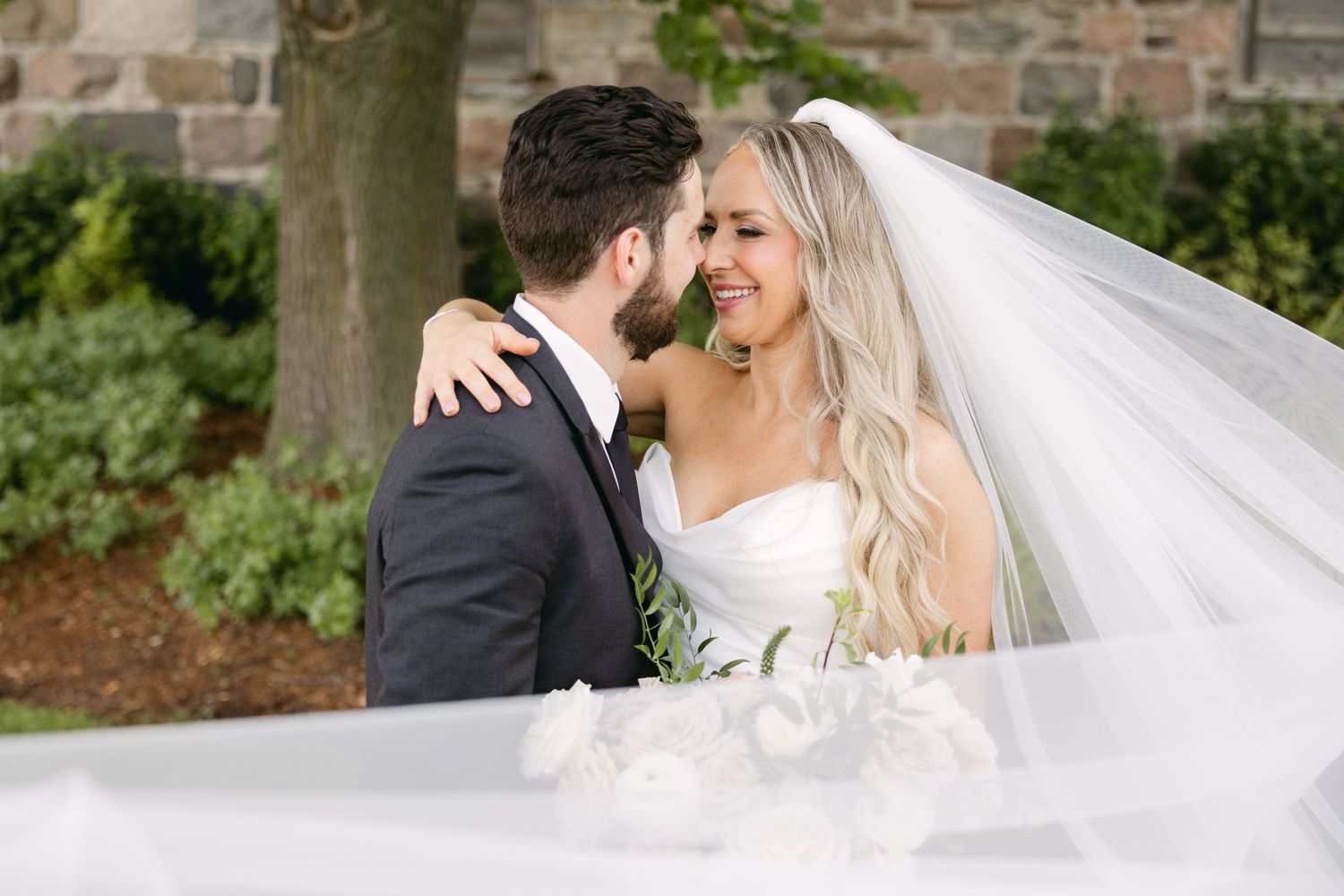 Romantic wedding portraits captured outdoors with flowing white veil.