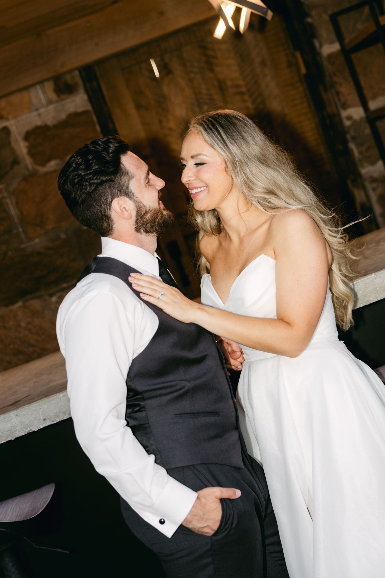 Newlyweds share an intimate dance moment in a dimly lit rustic venue.