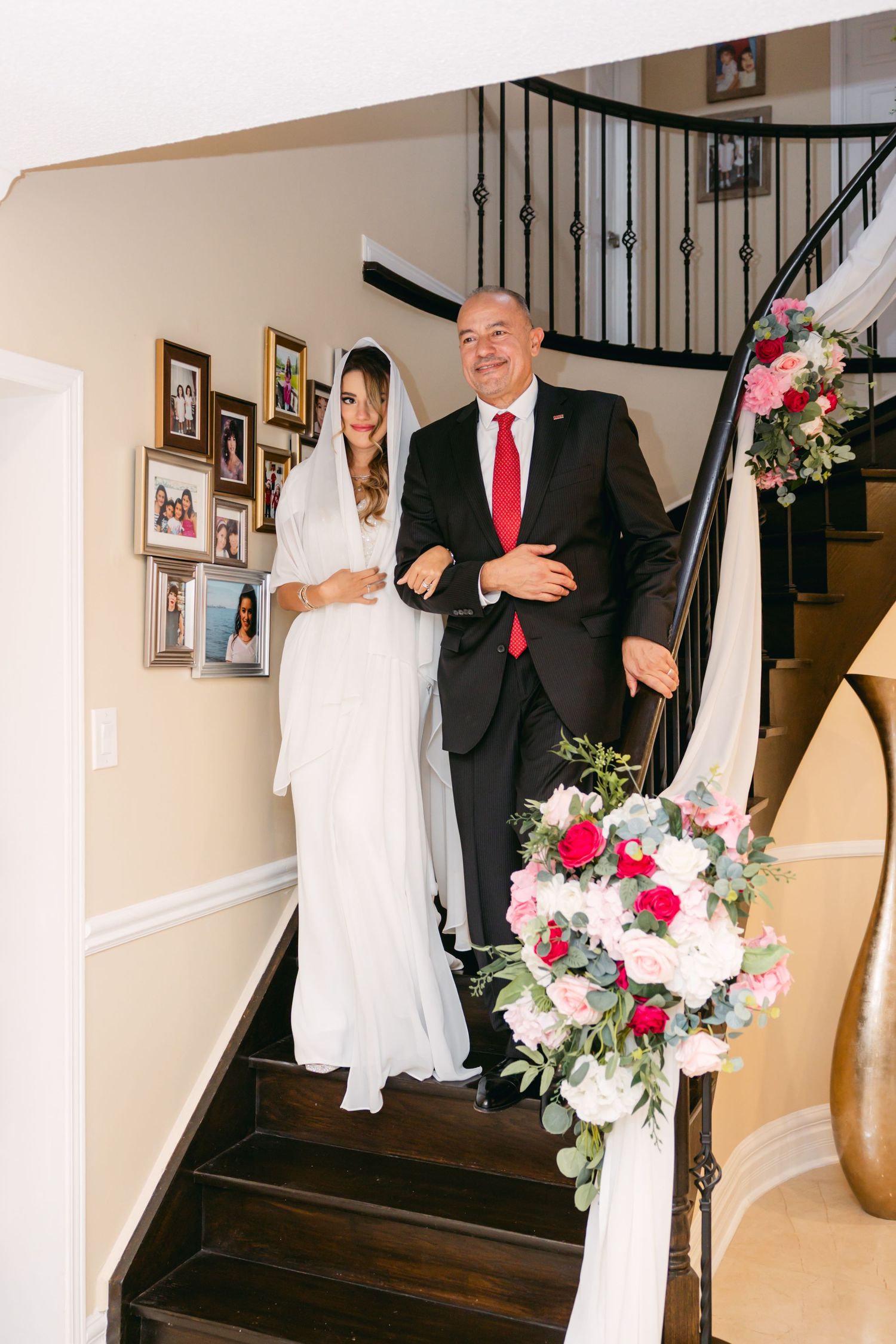 Wedding moments unfold on a staircase with beautiful floral arrangements and white drapery.