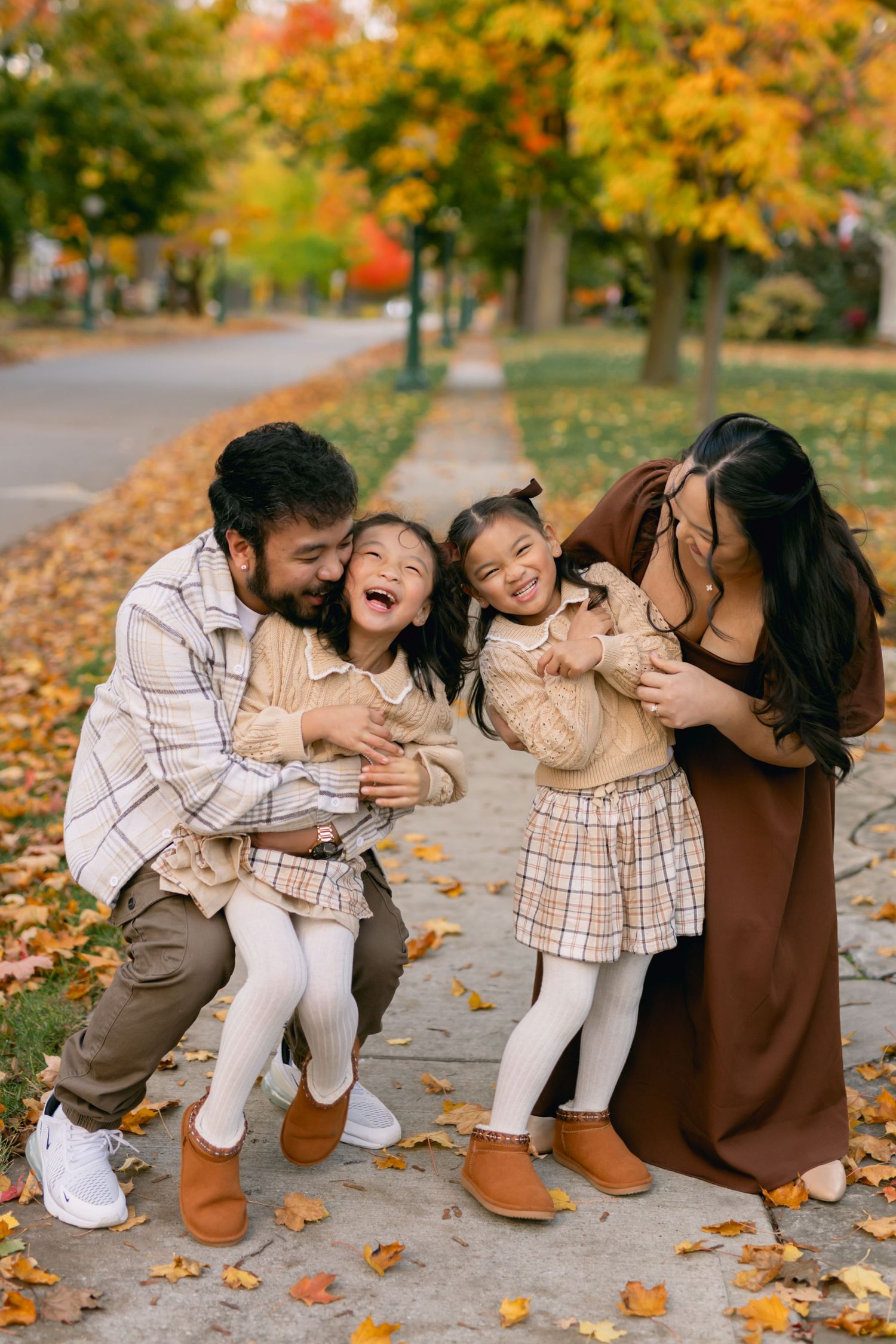 A family sharing playful moments together on a leaf-covered path during autumn.