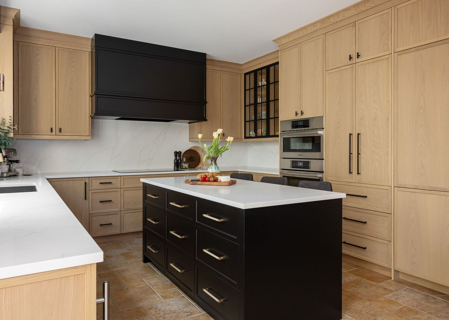 Spacious kitchen with natural wood cabinets, black base units, and white quartz countertops.