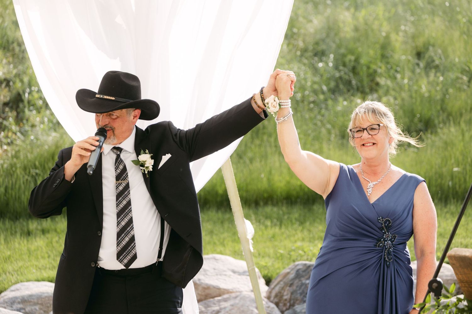 Wedding entertainers perform during outdoor celebration with white tent and scenic backdrop.