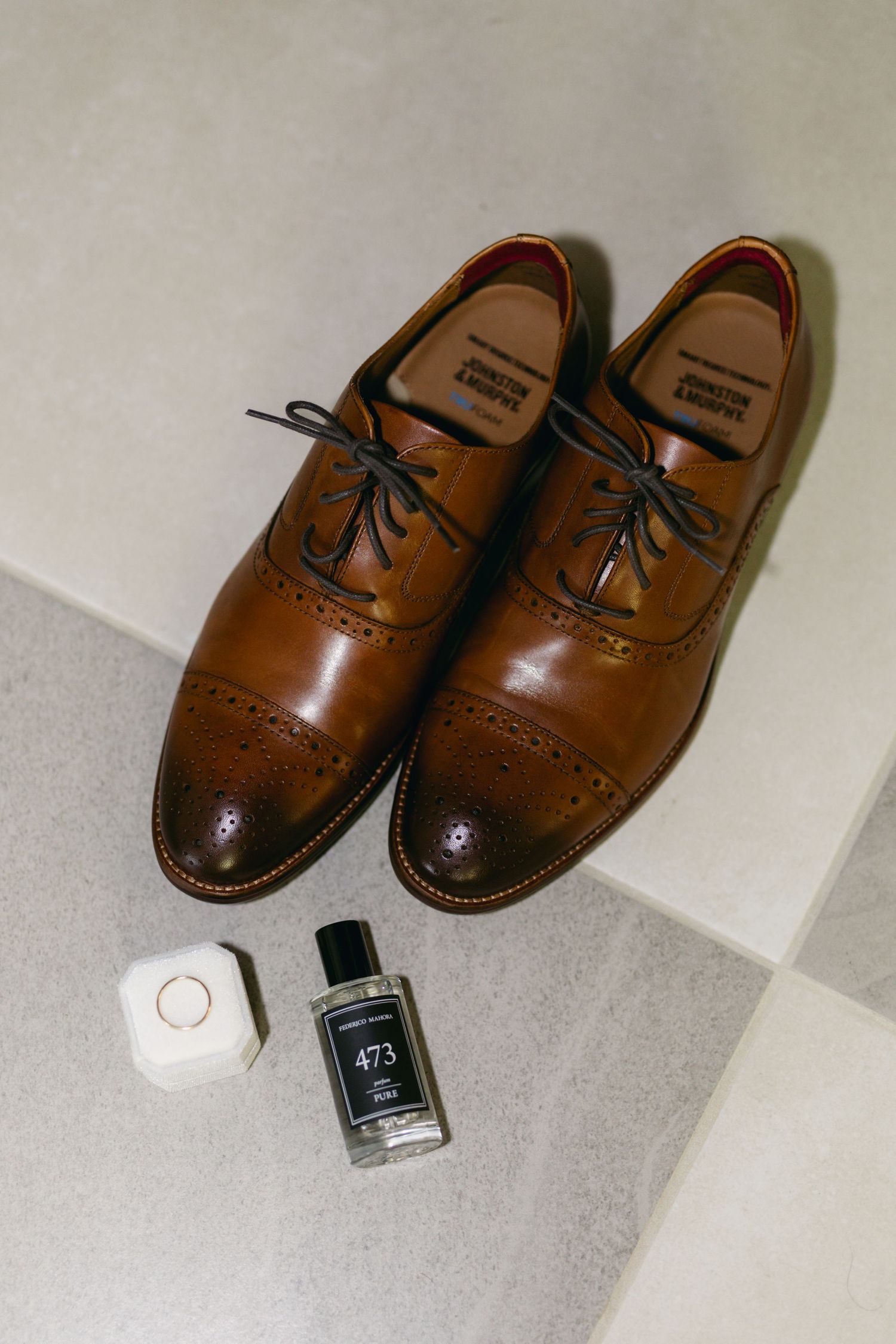Brown leather dress shoes with black nail polish and laces on white surface.