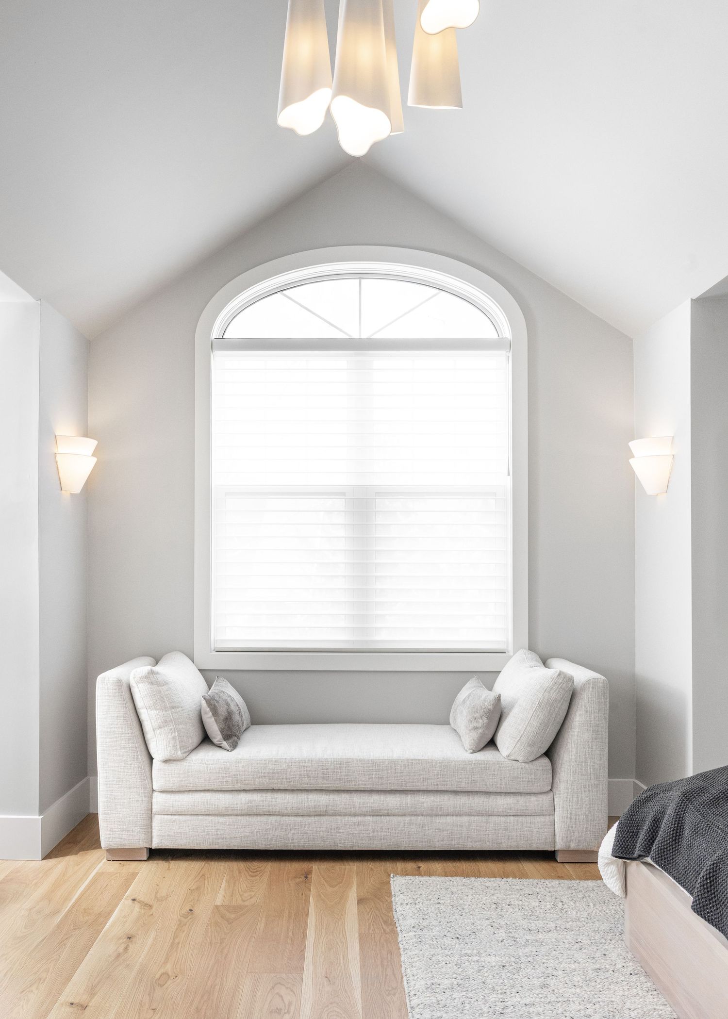 Bright sitting area with arched window, white walls, and contemporary sofa beneath vaulted ceiling.
