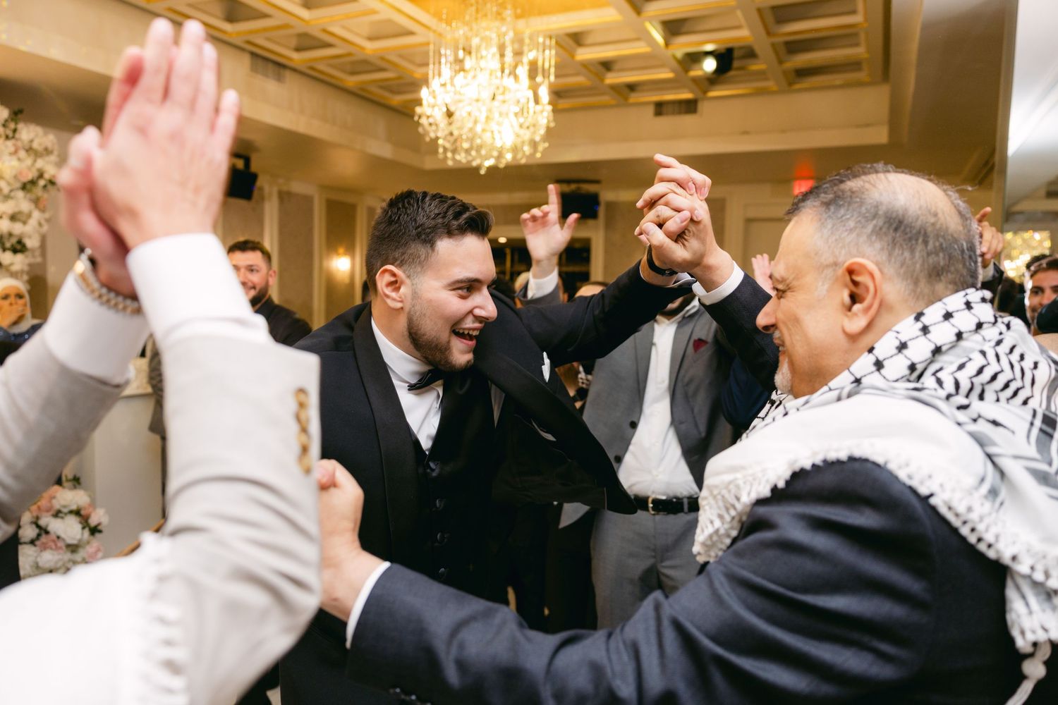Guests celebrate with raised hands and enthusiastic expressions at an elegant indoor reception.
