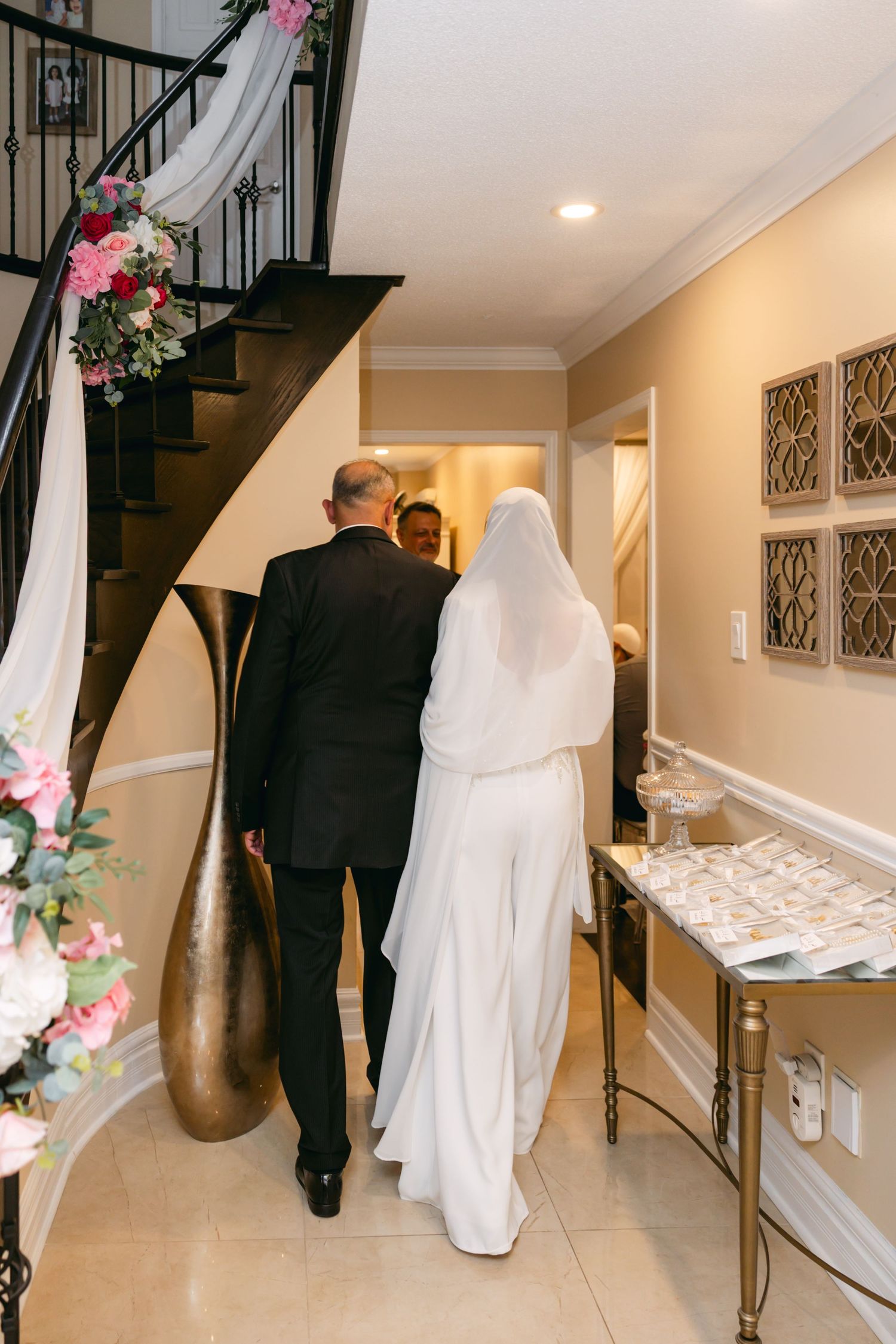 Wedding ceremony preparations in an elegant hallway with marble floors and dark railings.