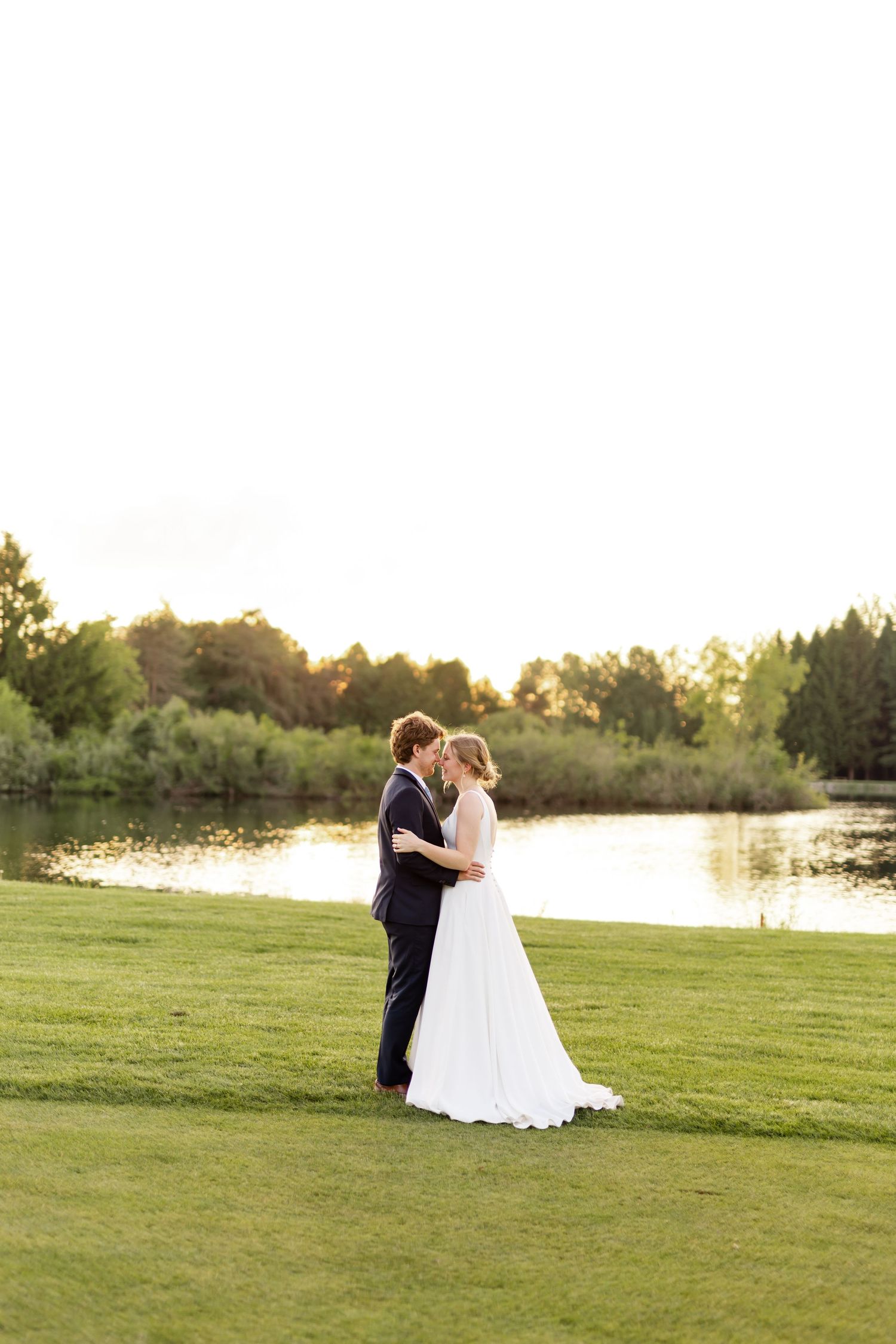 A romantic sunset wedding photo with the couple silhouetted against a lake.