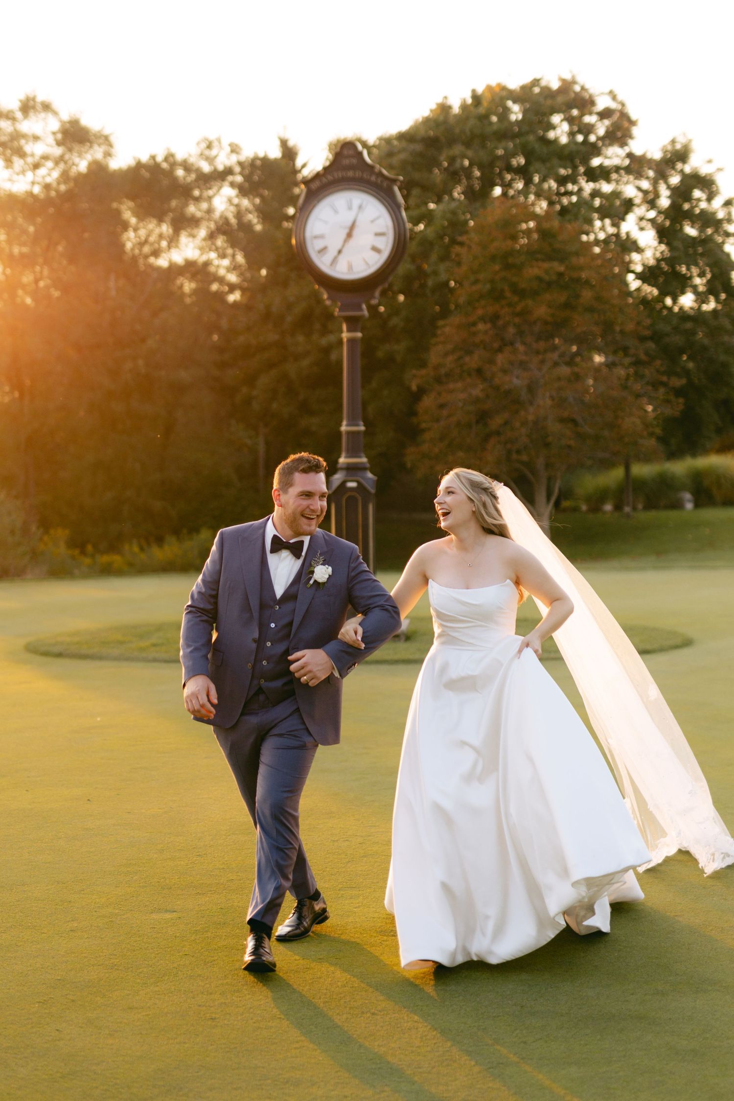Playful wedding couple dances and runs across golf course during golden hour photography.