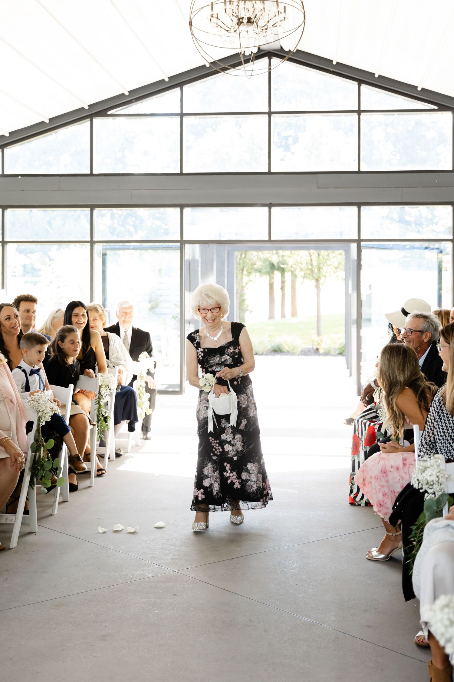 Modern white tent wedding venue with glass walls and elegant chandelier lighting.