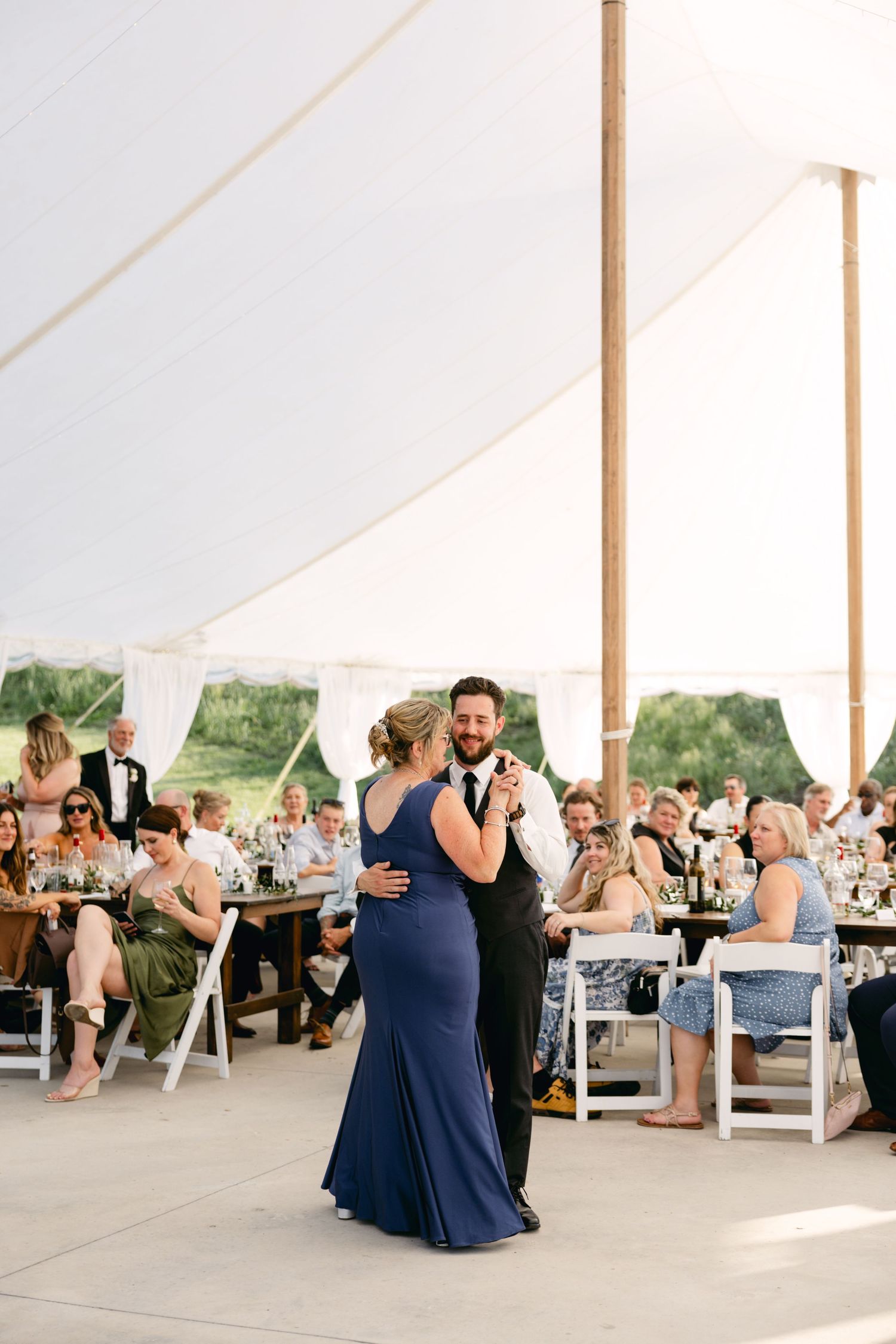 Wedding guests share dances under an elegant white tent reception venue.