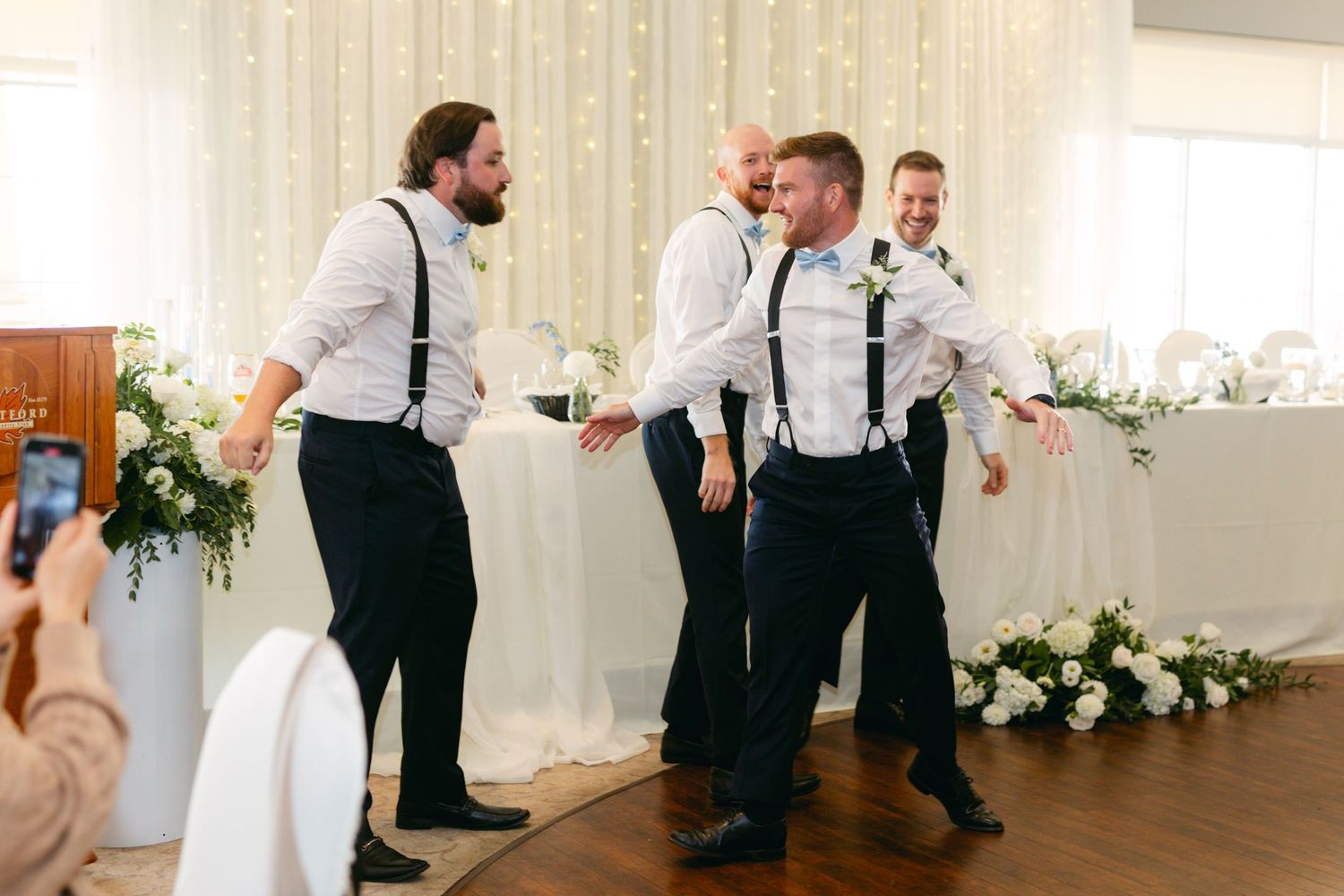 Wedding party members performing synchronized dance routine in an elegant reception hall.