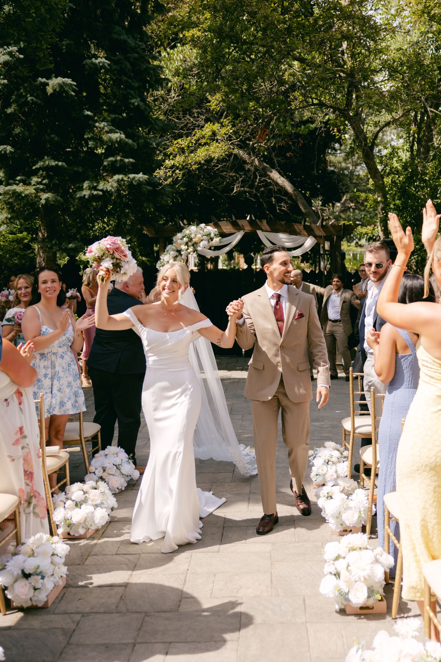 Wedding party celebrates with energetic poses and movements on a stone patio.