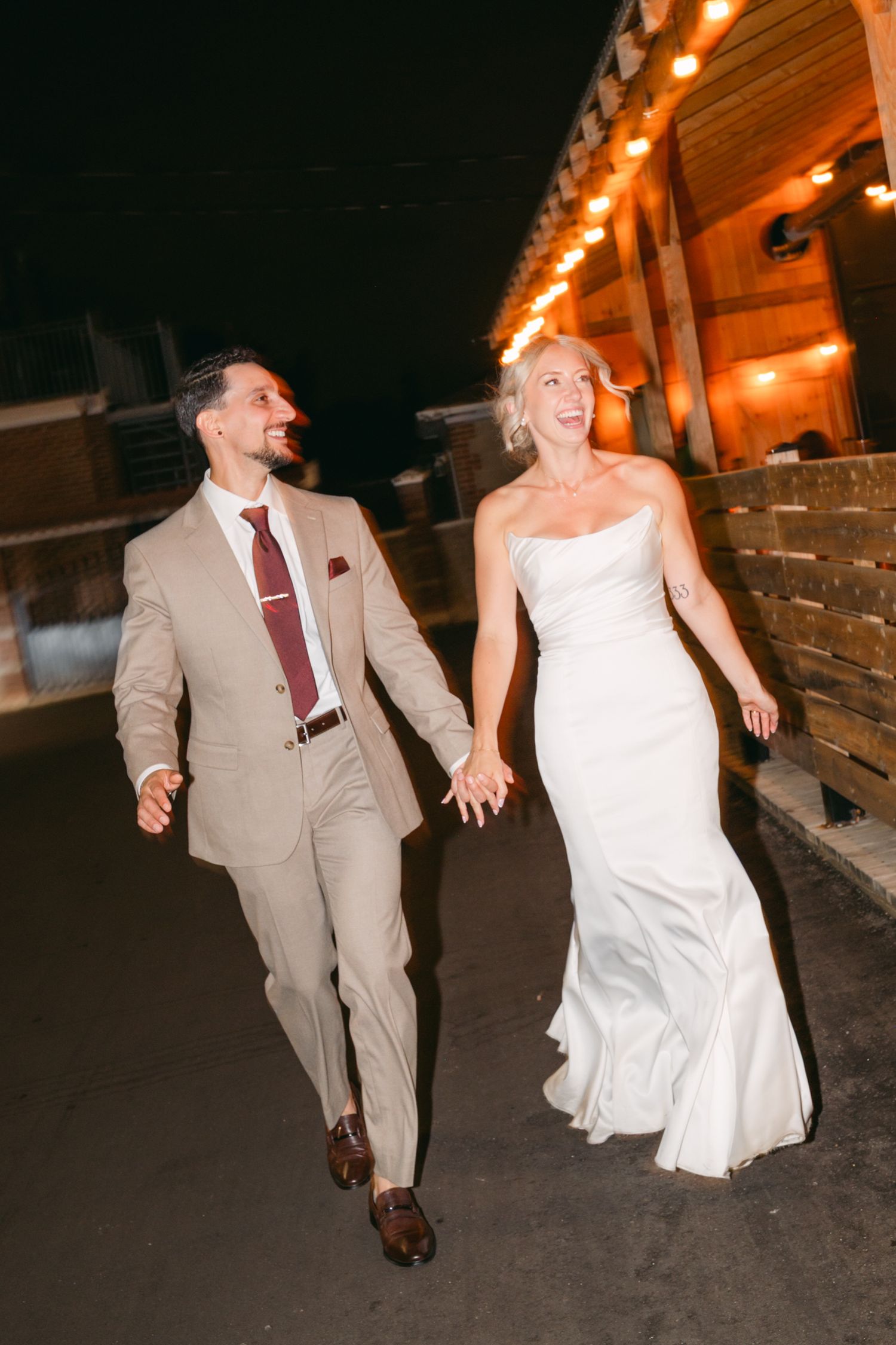 Couple walking together at night under venue lighting in formal attire.