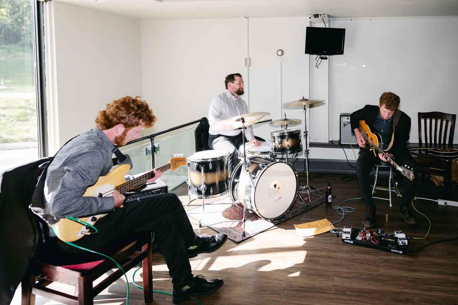 Band members set up musical equipment in bright indoor venue space.