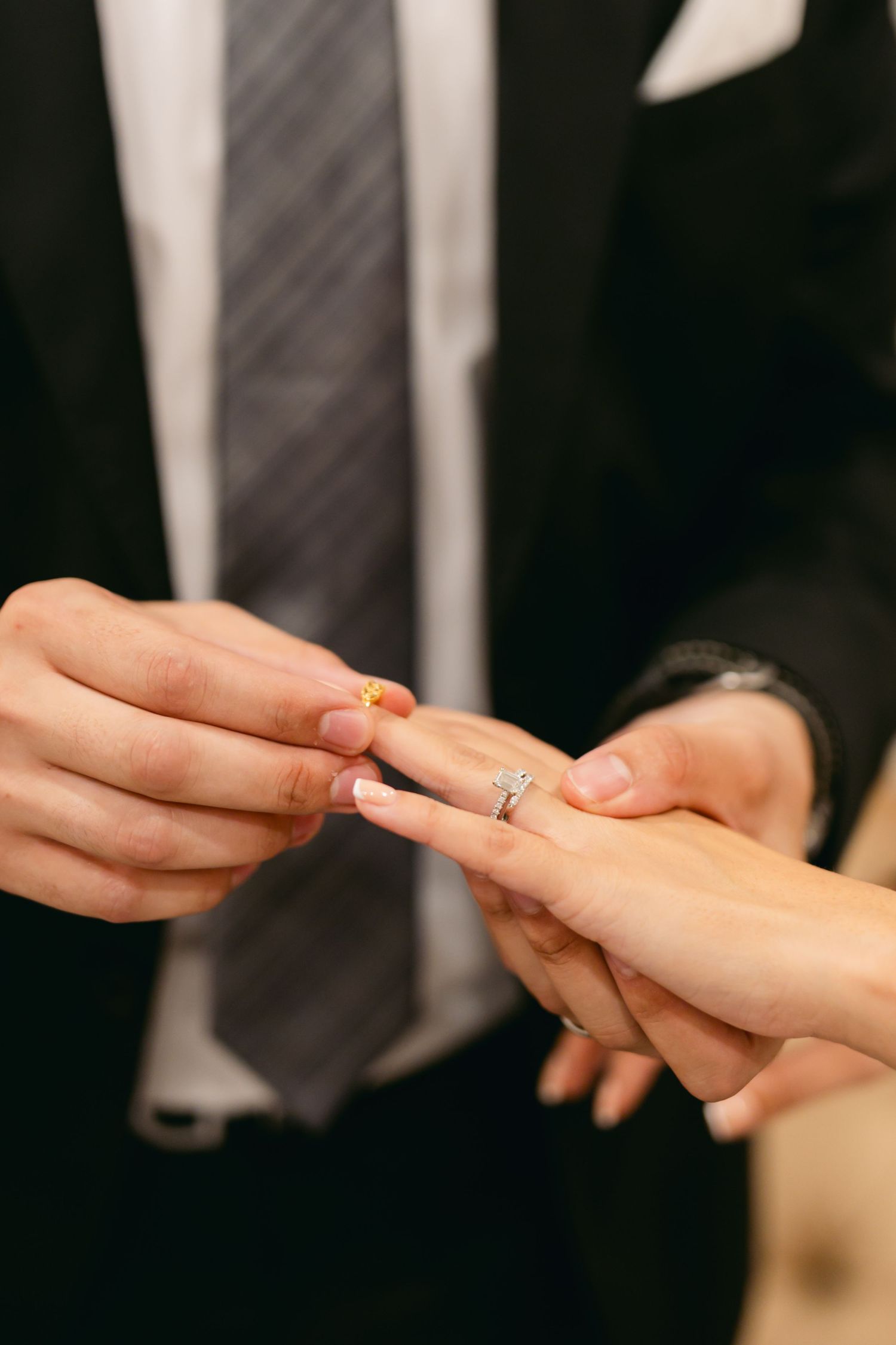 Close-up shot of hands exchanging rings during a ceremony.