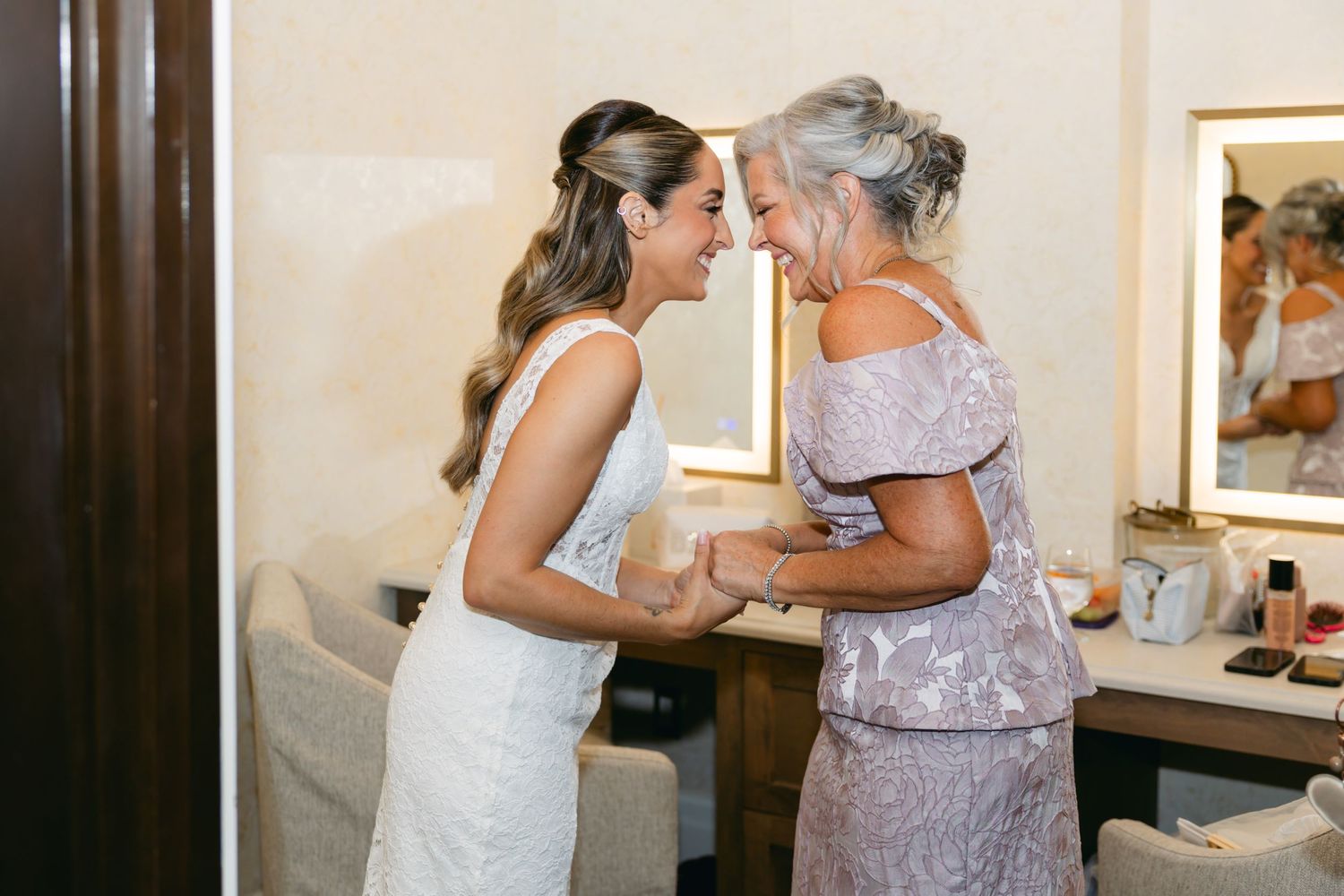 Two women share an emotional embrace in elegant formal dresses at a special event.