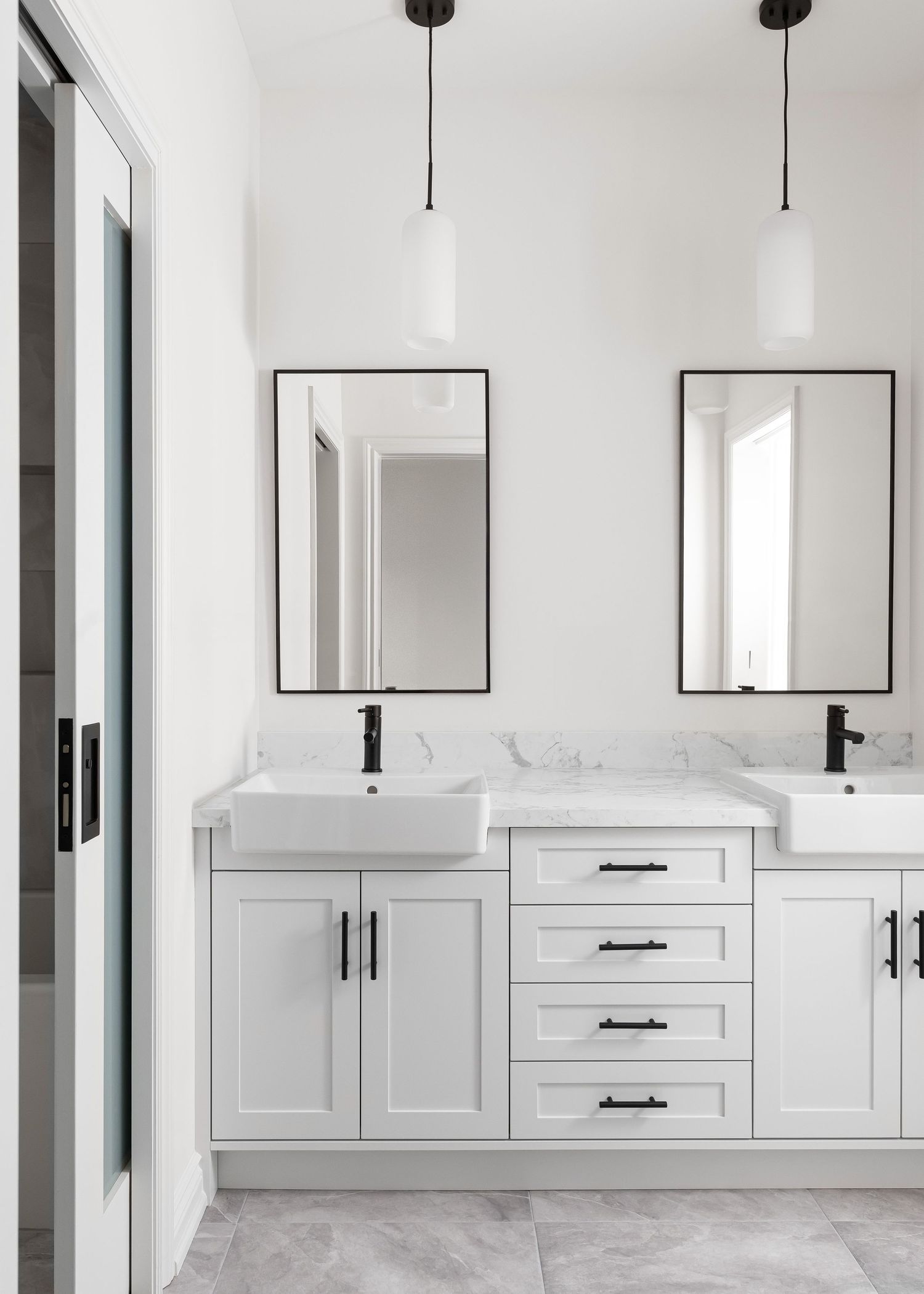 Bright white double vanity bathroom with black-framed mirrors and pendant lights.