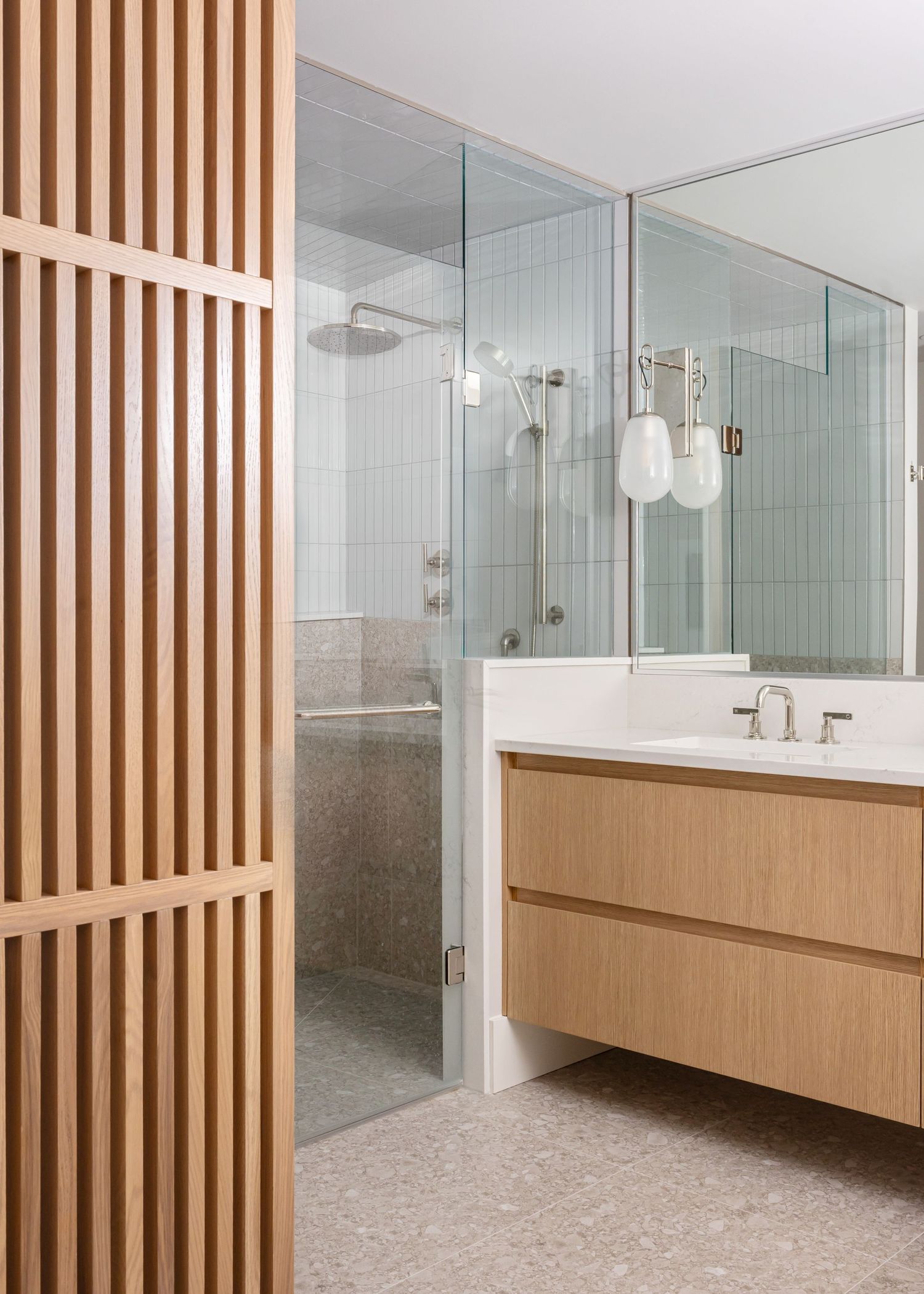 Modern bathroom with wooden slat divider, floating vanity, and glass shower enclosure.