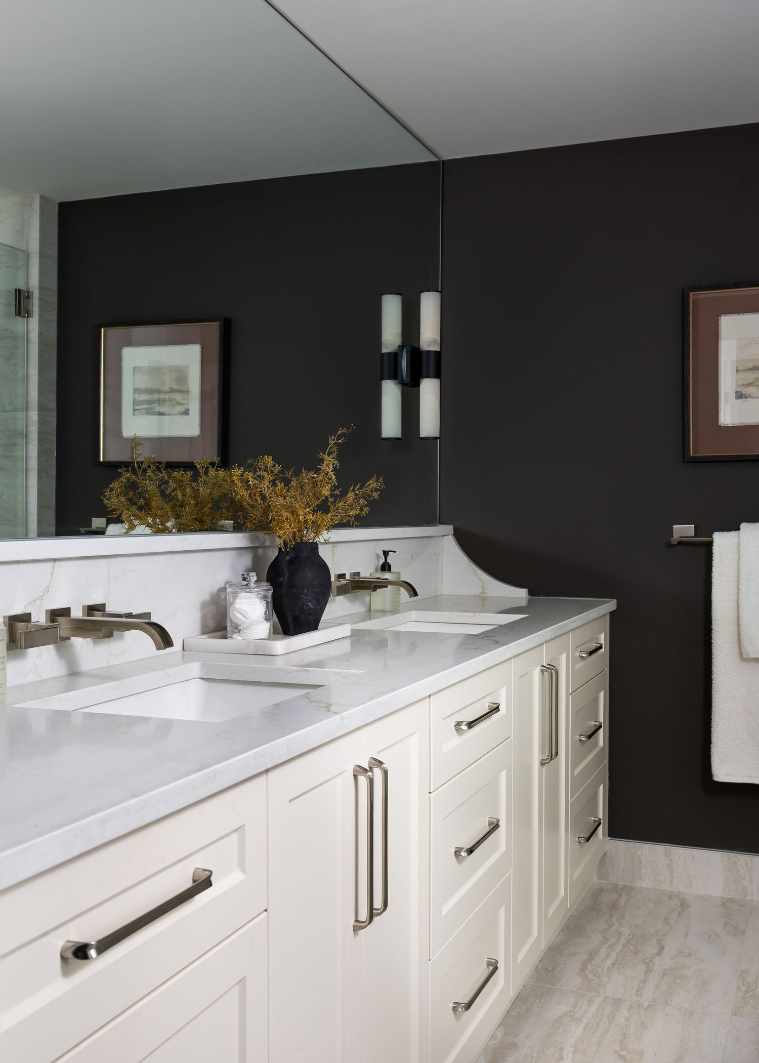 White kitchen cabinetry with dark walls, marble countertops, and modern hardware details.