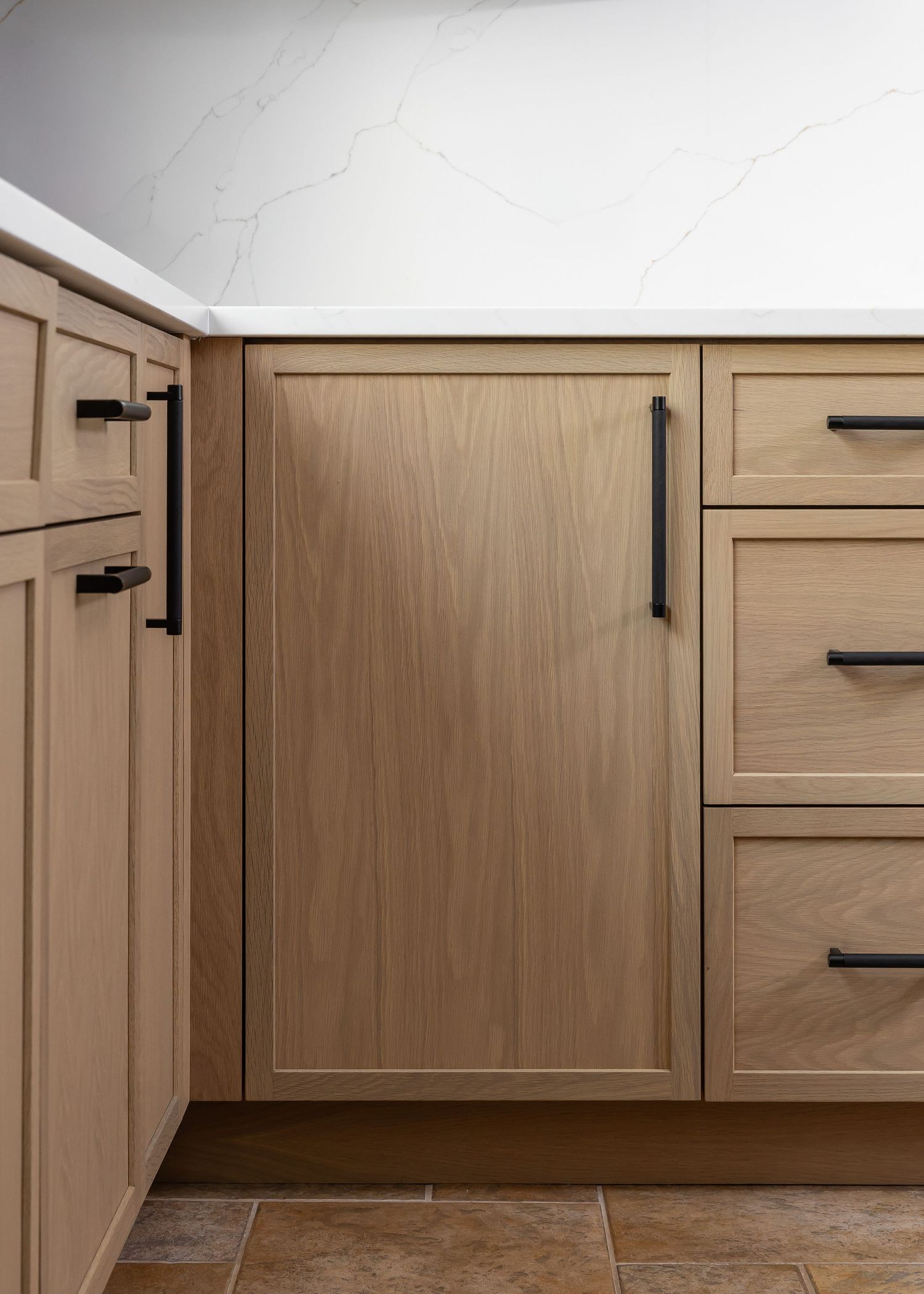 Lower kitchen cabinet storage solutions with wooden drawer fronts and black handles.