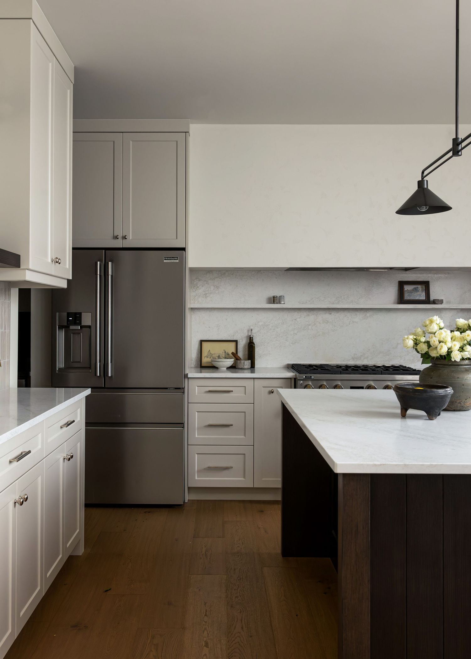 Spacious kitchen featuring white cabinetry, dark wood island, and pendant lighting with panoramic windows.