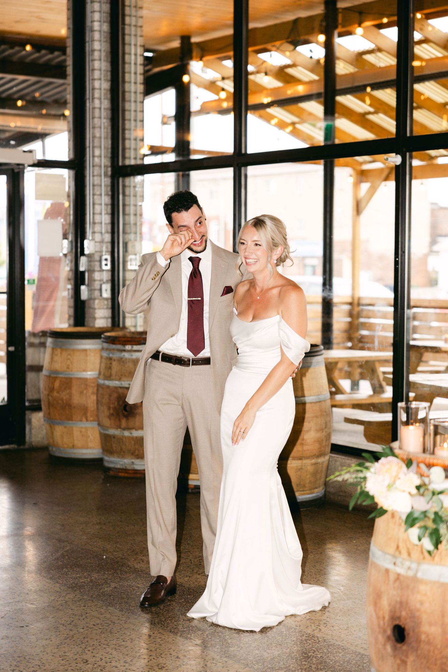 Wedding couple shares a joyful dance together in a rustic venue with wooden barrels and exposed beams.