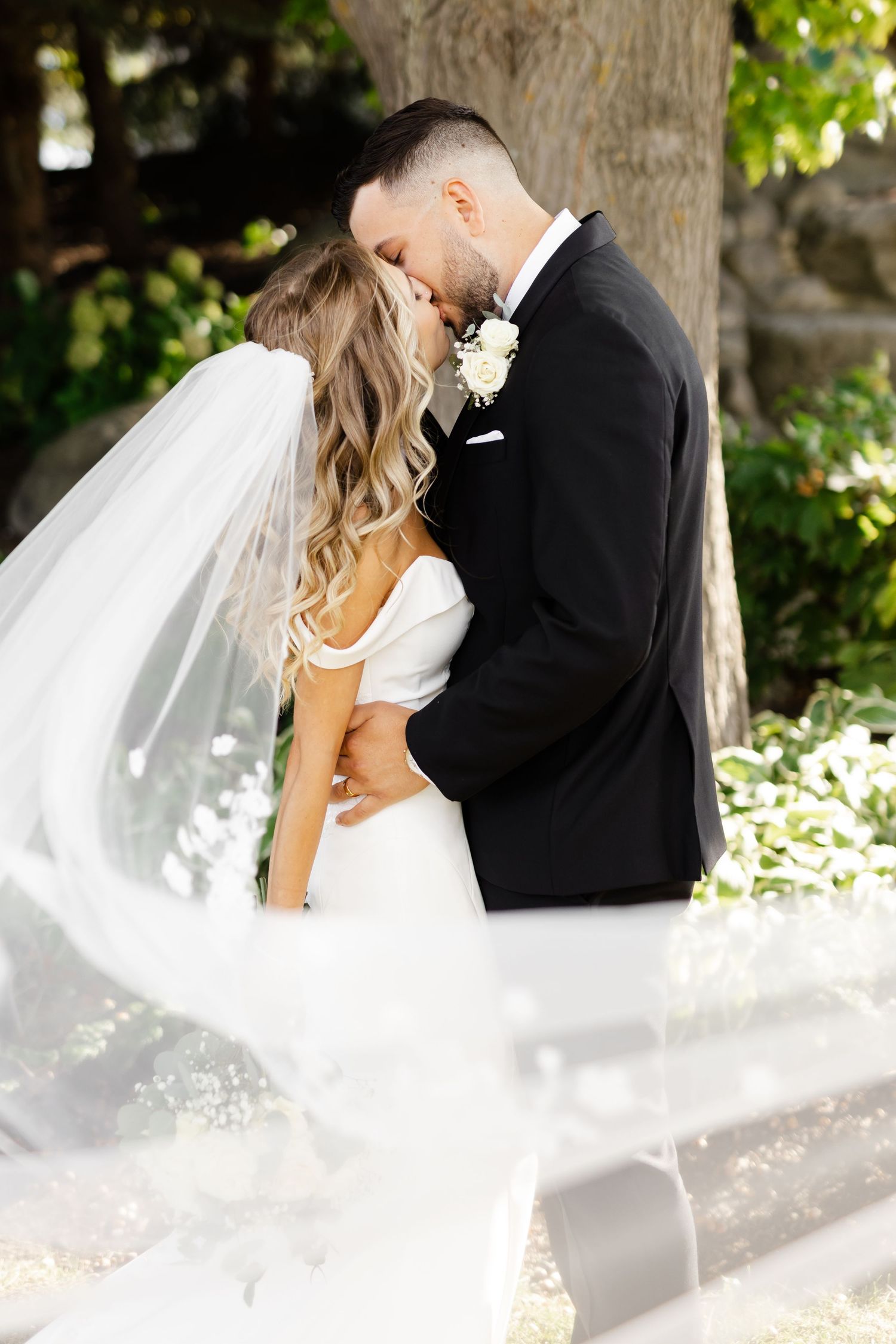 Romantic wedding portrait with flowing veil in natural sunlight.