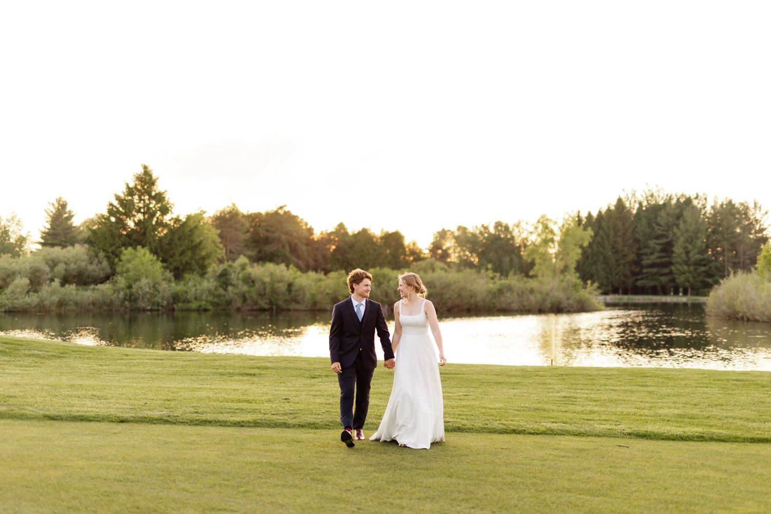 A serene lakeside wedding scene with distant figures against the sunset.
