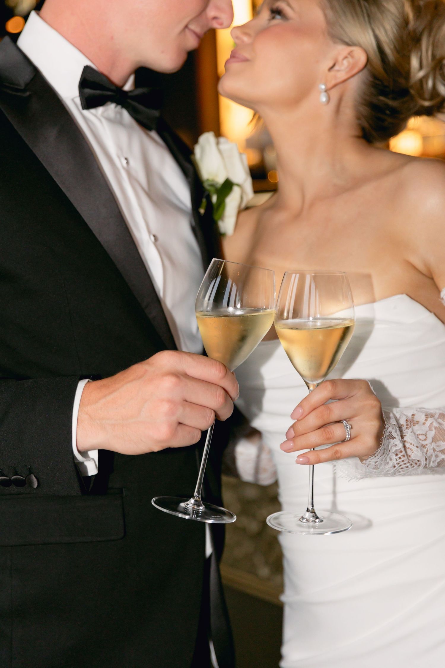 Bride and groom clinking champagne glasses together at elegant wedding reception celebration.
