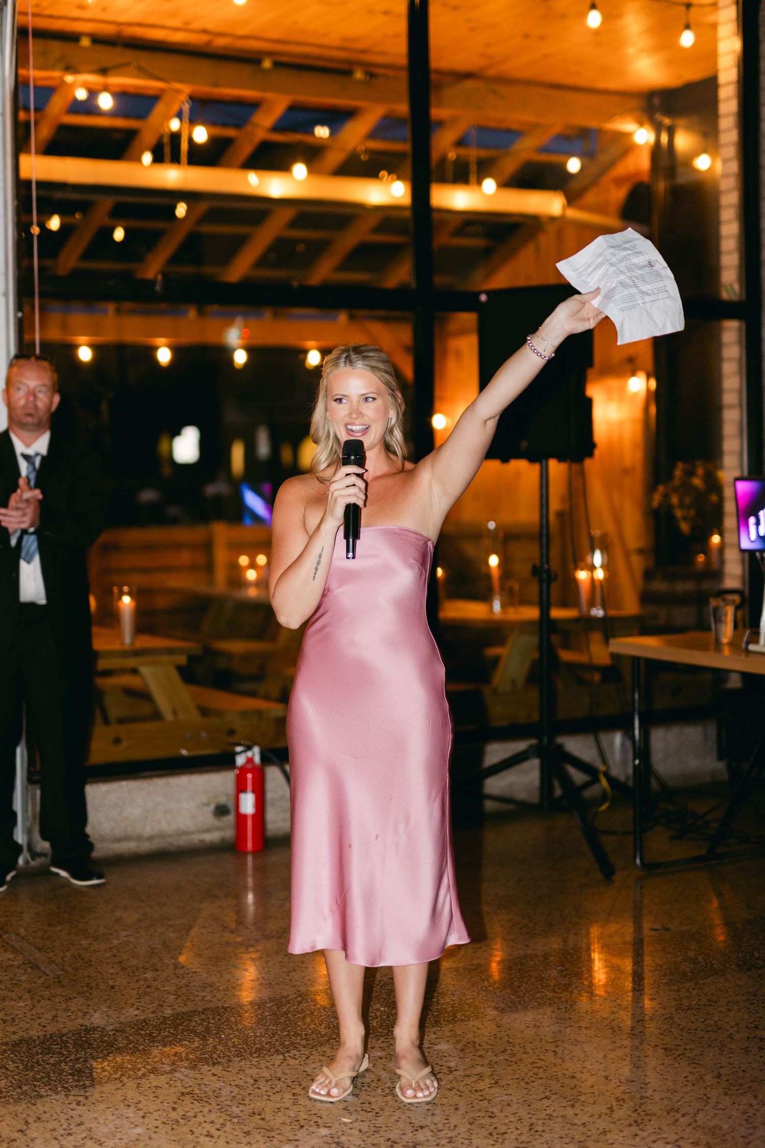 Person in pink dress performs energetically on dance floor under warm venue lighting.