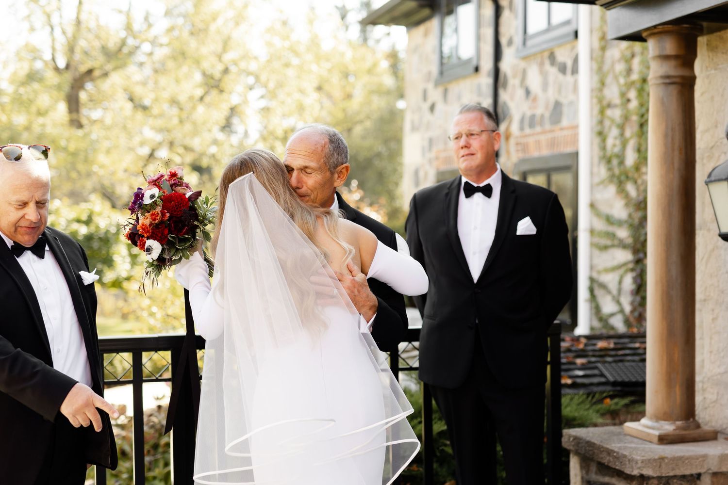 A bride and groom share an intimate moment during their first look outside a rustic stone venue.