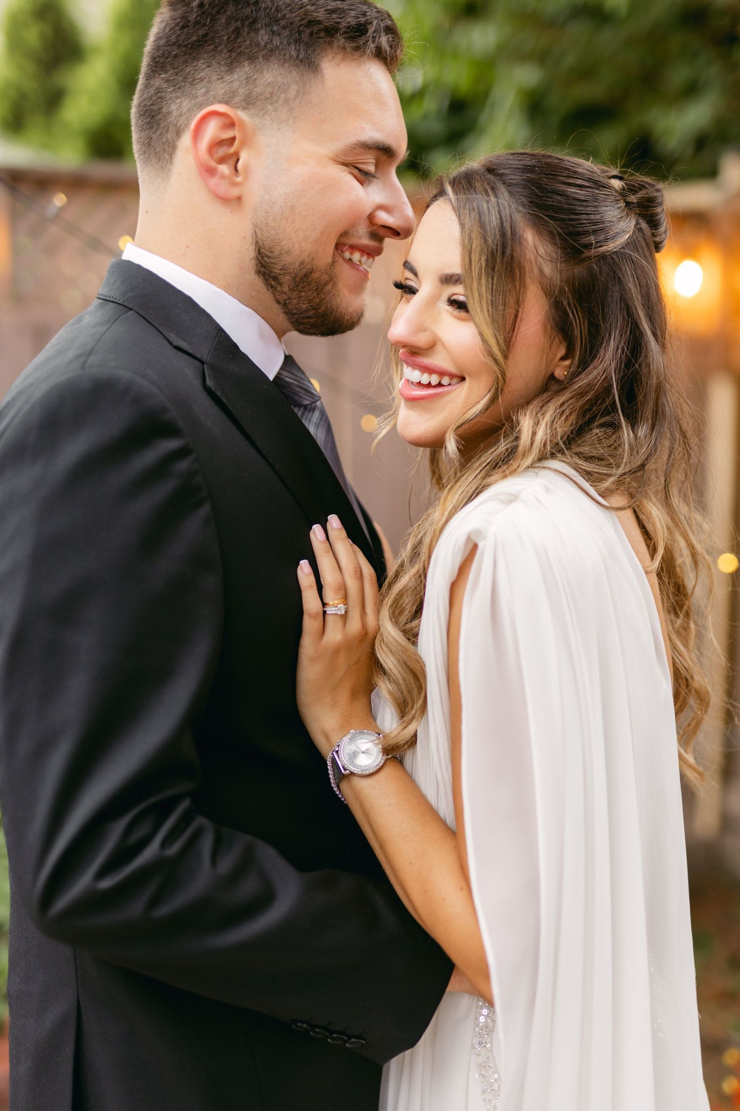 Joyful wedding couple sharing intimate moment in outdoor garden setting.
