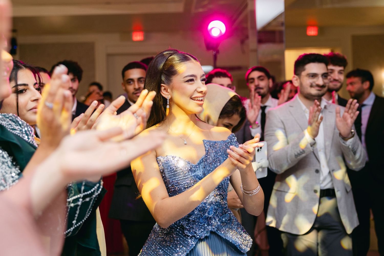 Wedding reception dance party with colorful lighting and enthusiastic guests celebrating.
