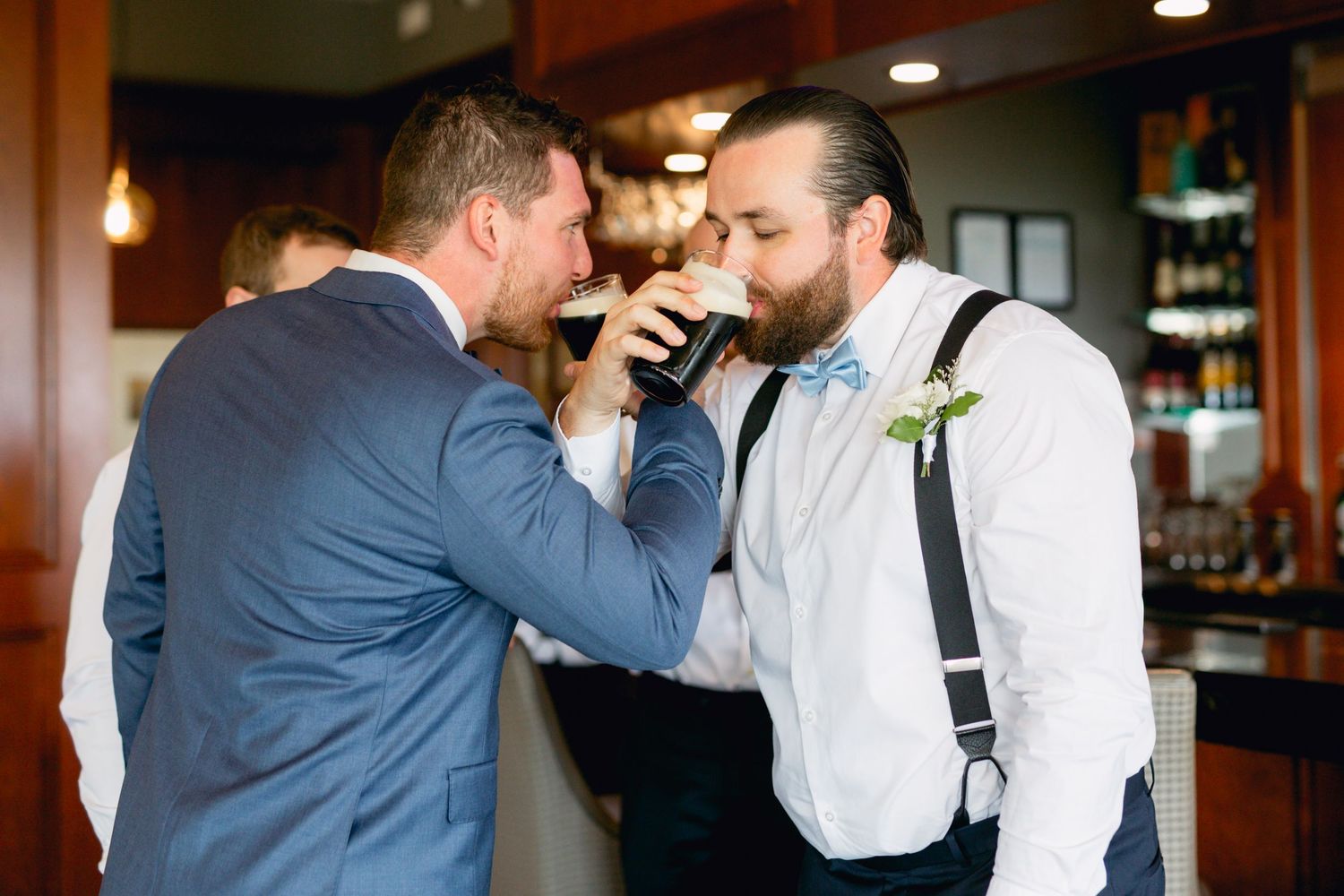 Two wedding party members share a toast at the bar during celebration.