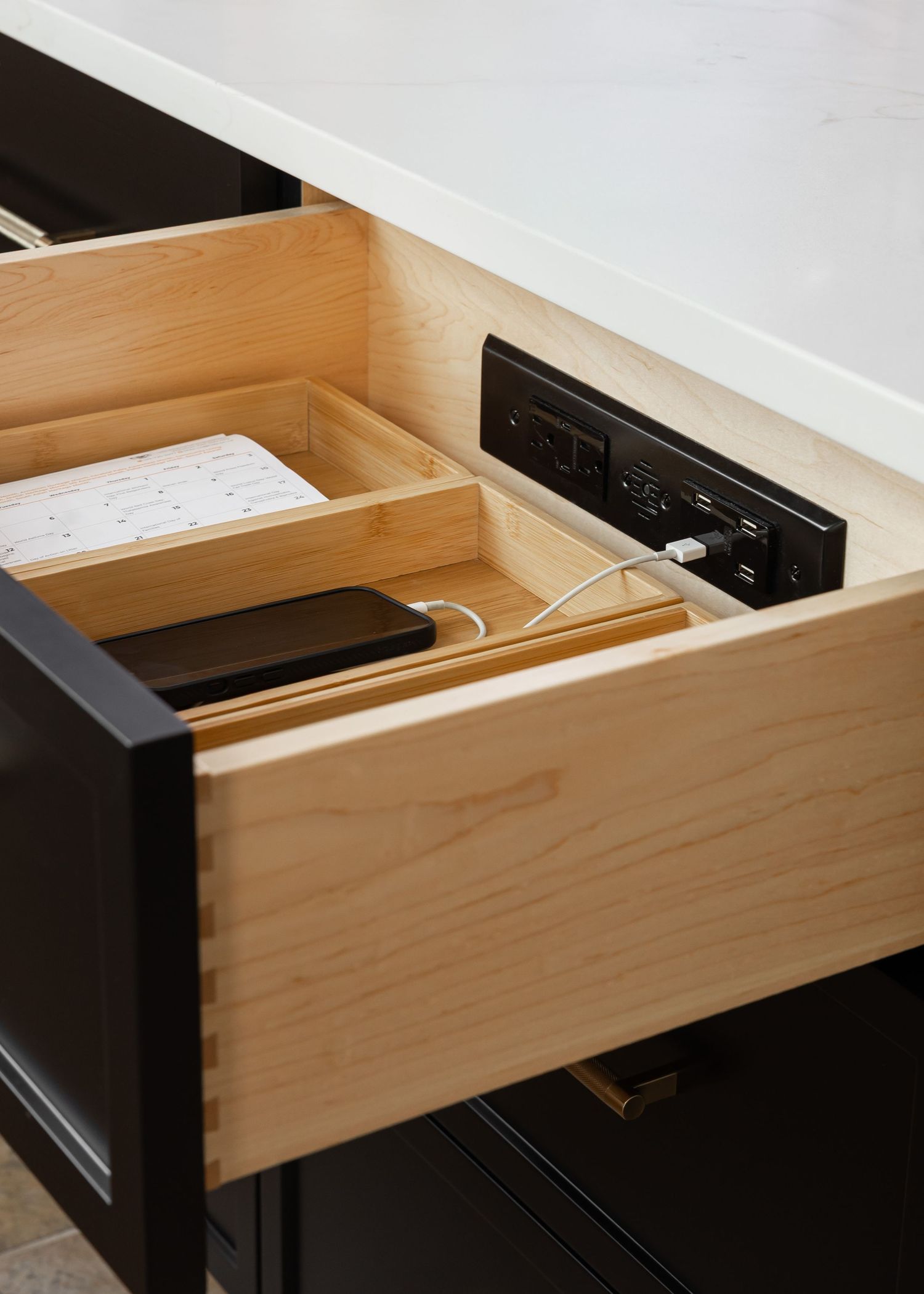 Built-in power outlet and charging station integrated into kitchen drawer design.