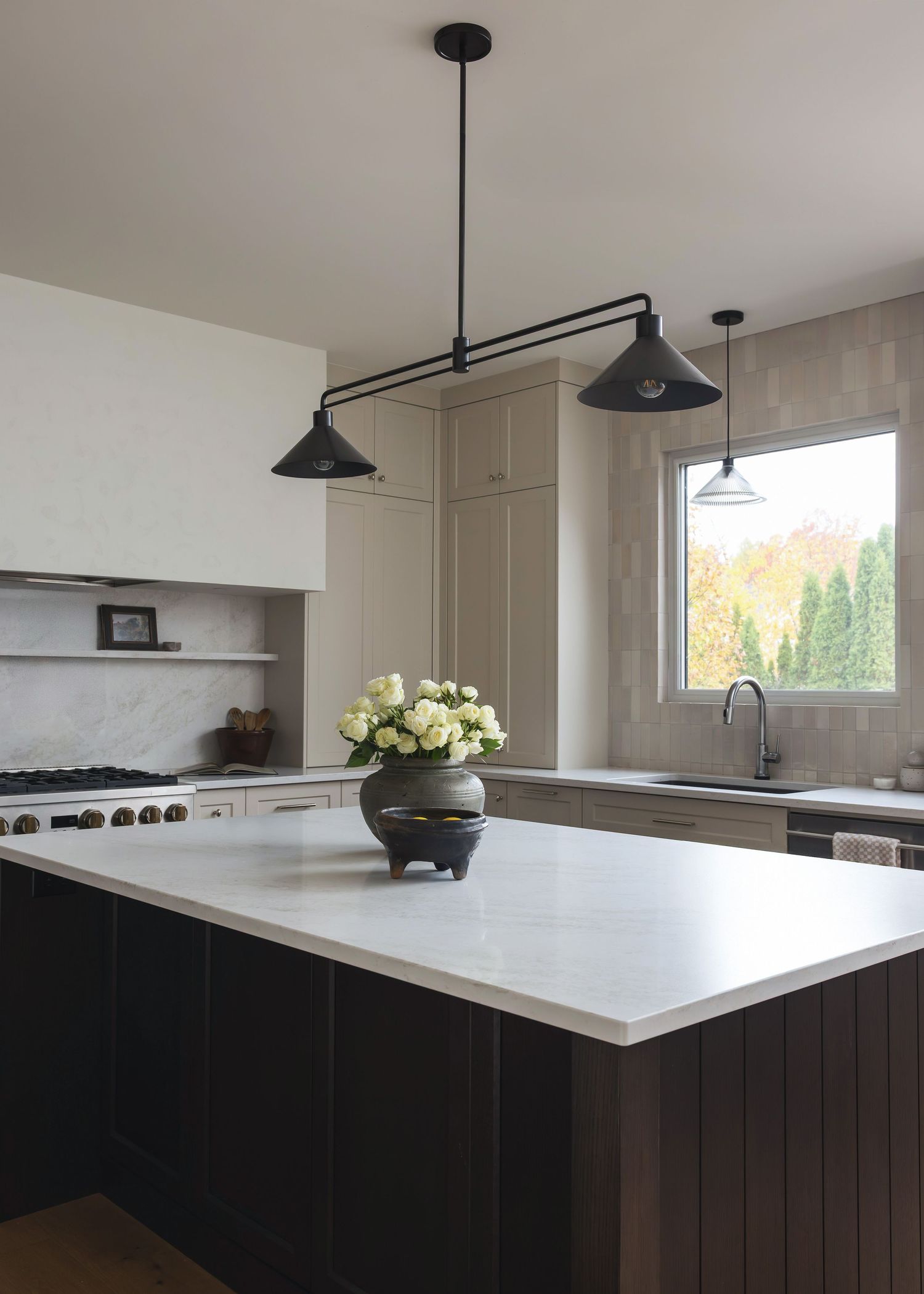 Contemporary kitchen island with black base and white countertop under modern pendant lighting.