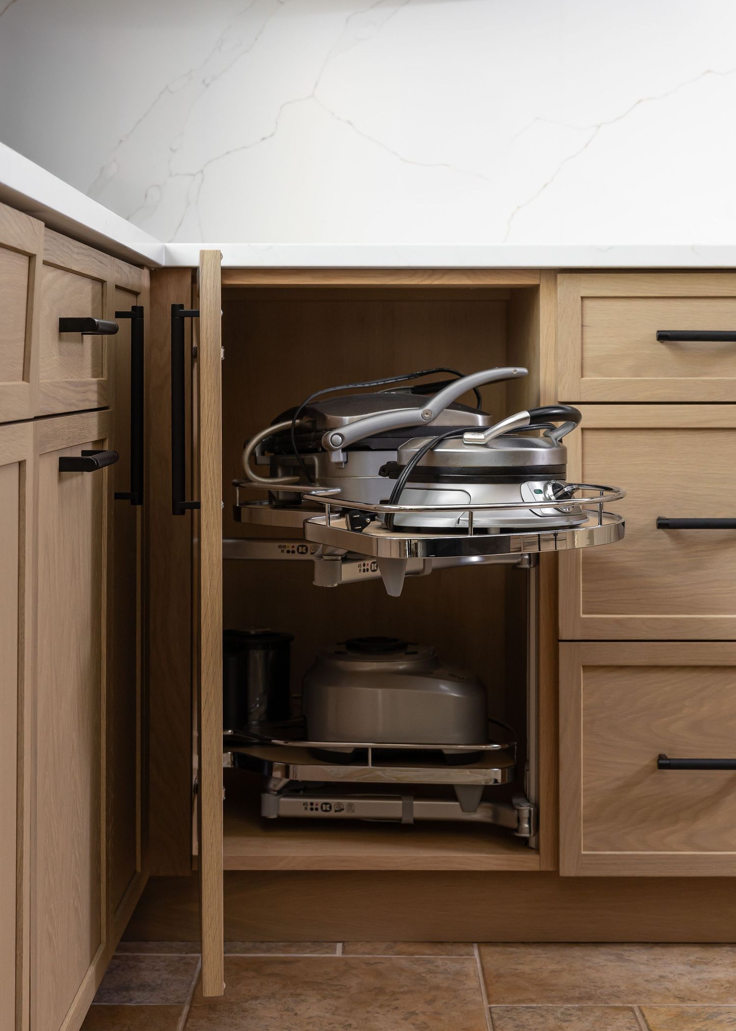 Hidden pull-out kitchen storage mechanisms revealed behind wood cabinet doors.