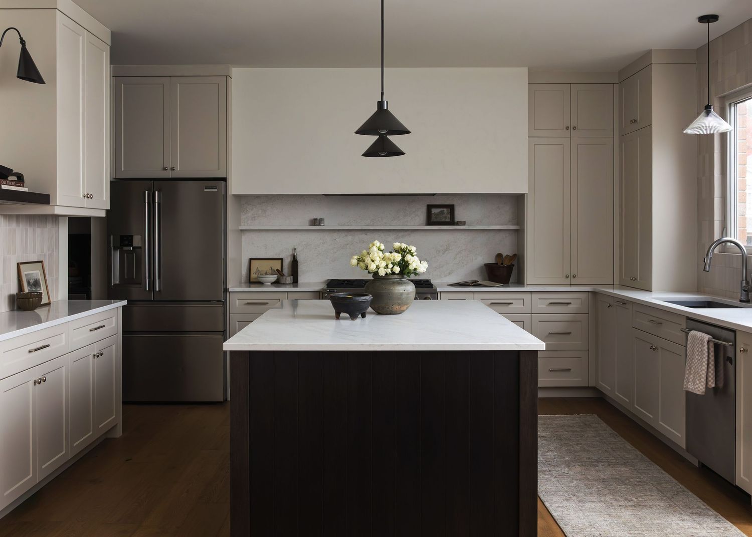 Modern kitchen with white cabinets, dark island, and hardwood floors showcasing an open concept design.