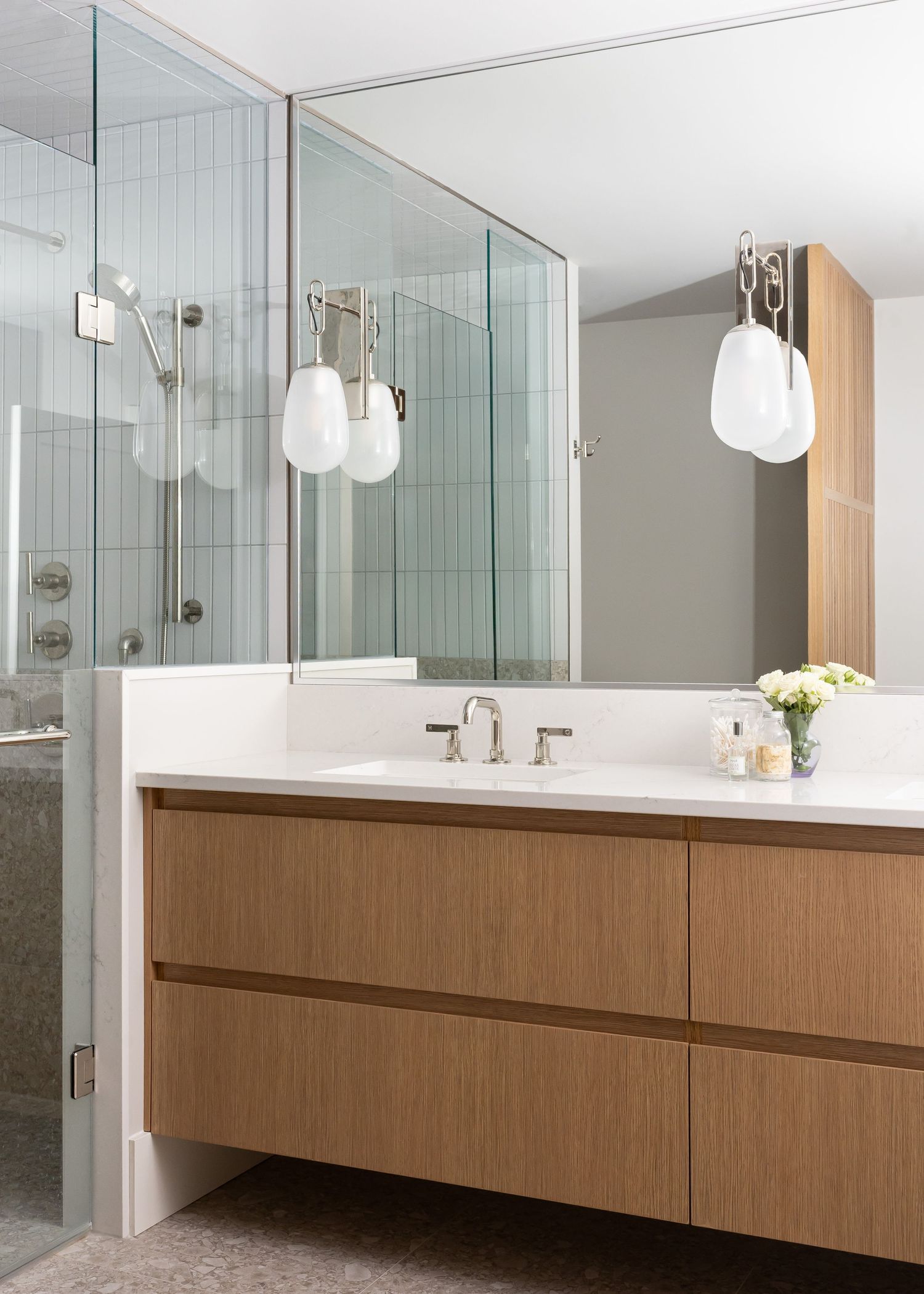 Luxurious bathroom featuring floating wood vanity, glass shower enclosure, and pendant lighting.