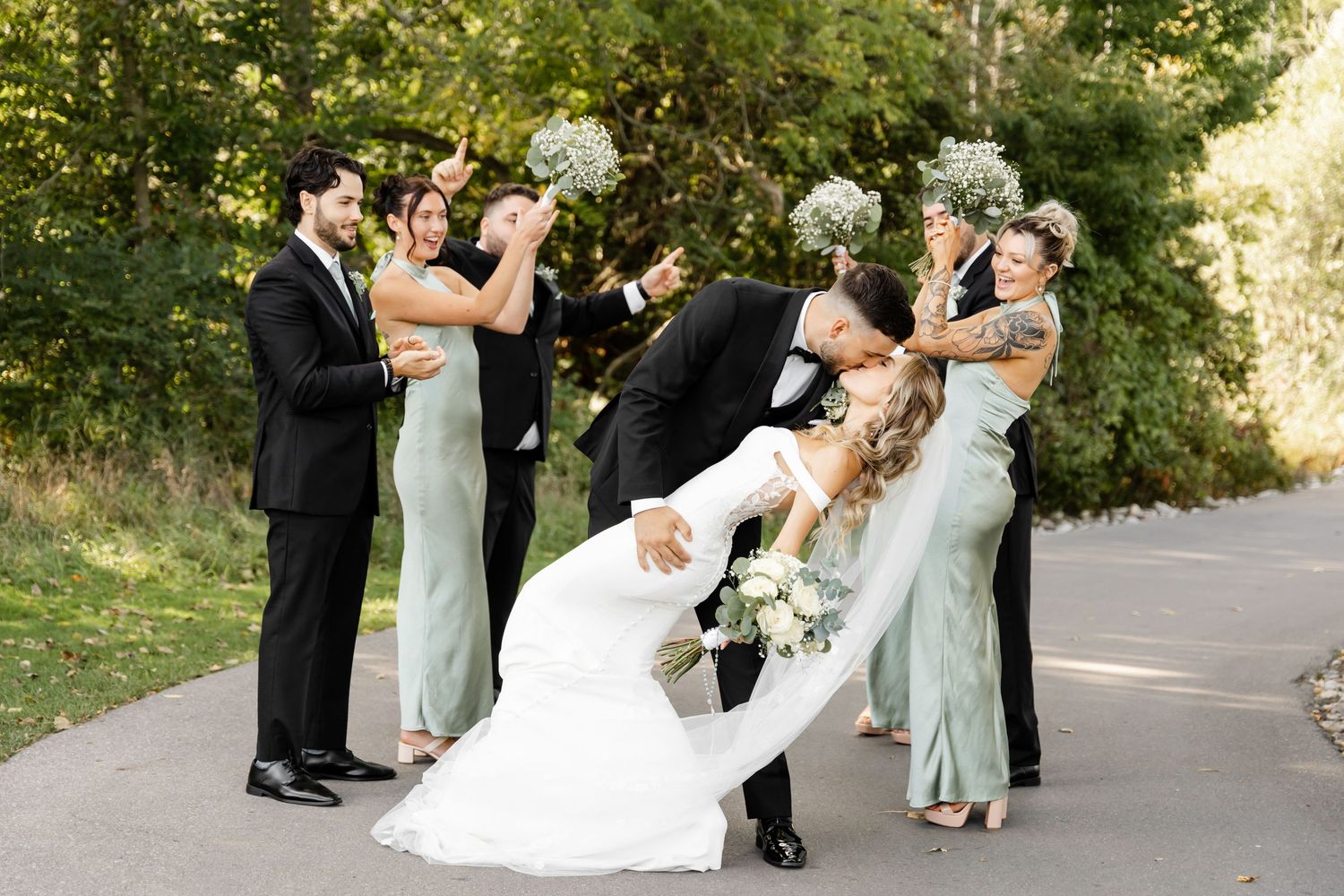 Wedding party dancing and posing together on outdoor pathway.